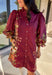 This burgundy button-down dress by Entro is a timeless piece with a fall-ready twist. Featuring a delicate floral print along the sides, it’s designed with a ruffled accent v-neckline for a touch of femininity. The elastic sleeves make for an easy, comfortable fit, while the full lining ensures effortless wear. With its rich color and flattering silhouette, this dress transitions seamlessly from day to night.
