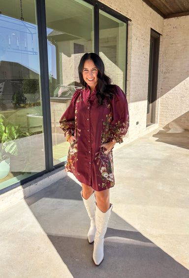 This burgundy button-down dress by Entro is a timeless piece with a fall-ready twist. Featuring a delicate floral print along the sides, it’s designed with a ruffled accent v-neckline for a touch of femininity. The elastic sleeves make for an easy, comfortable fit, while the full lining ensures effortless wear. With its rich color and flattering silhouette, this dress transitions seamlessly from day to night.