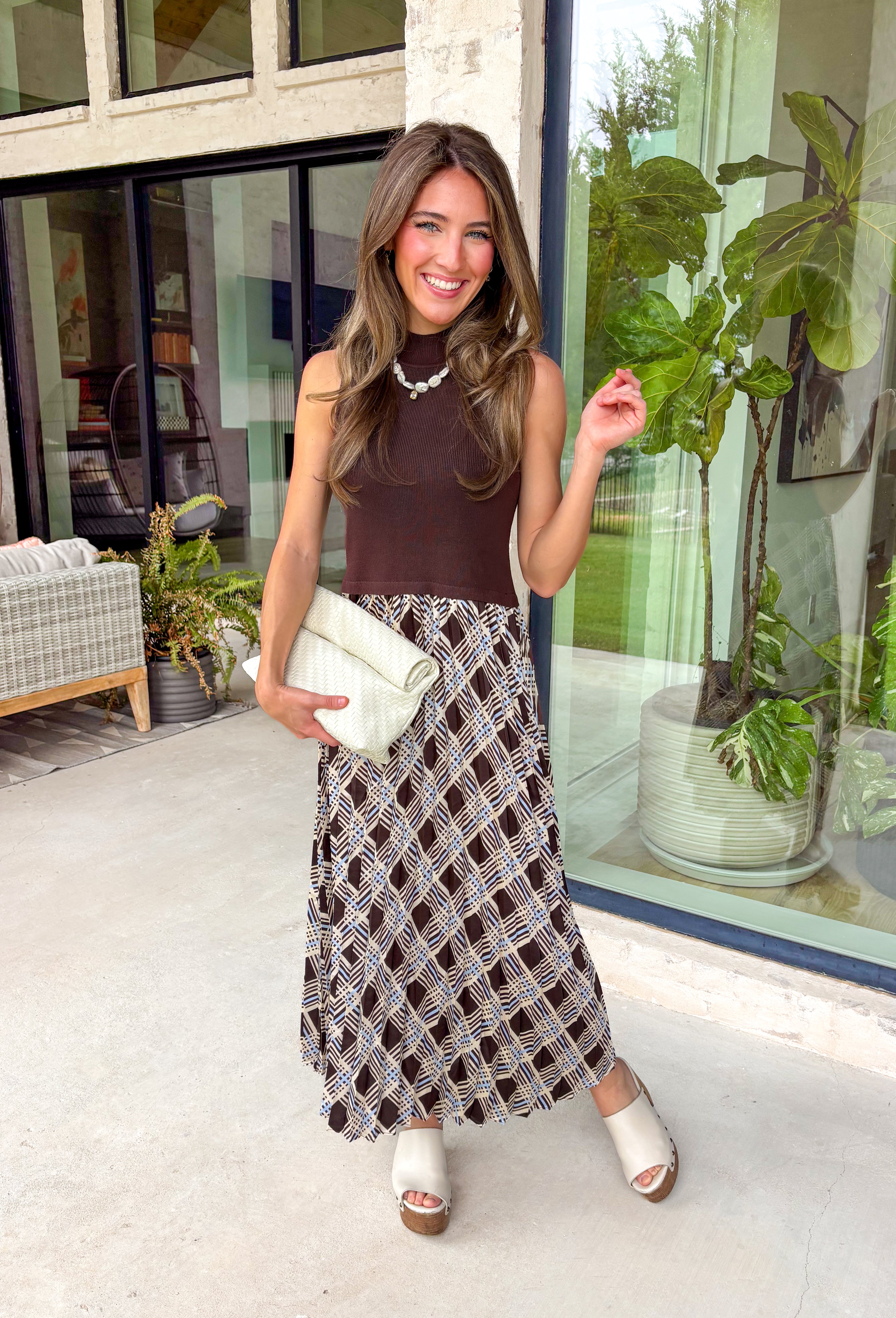 Elevate your fall wardrobe with this effortlessly elegant midi dress from Skies Are Blue. Featuring a rich brown sleeveless knit bodice with a classic mock neckline, this dress is beautifully complemented by a flowing pleated skirt showcasing an abstract print with subtle pops of blue. The combination of textures creates a polished, sophisticated look that's both comfortable and eye-catching. 