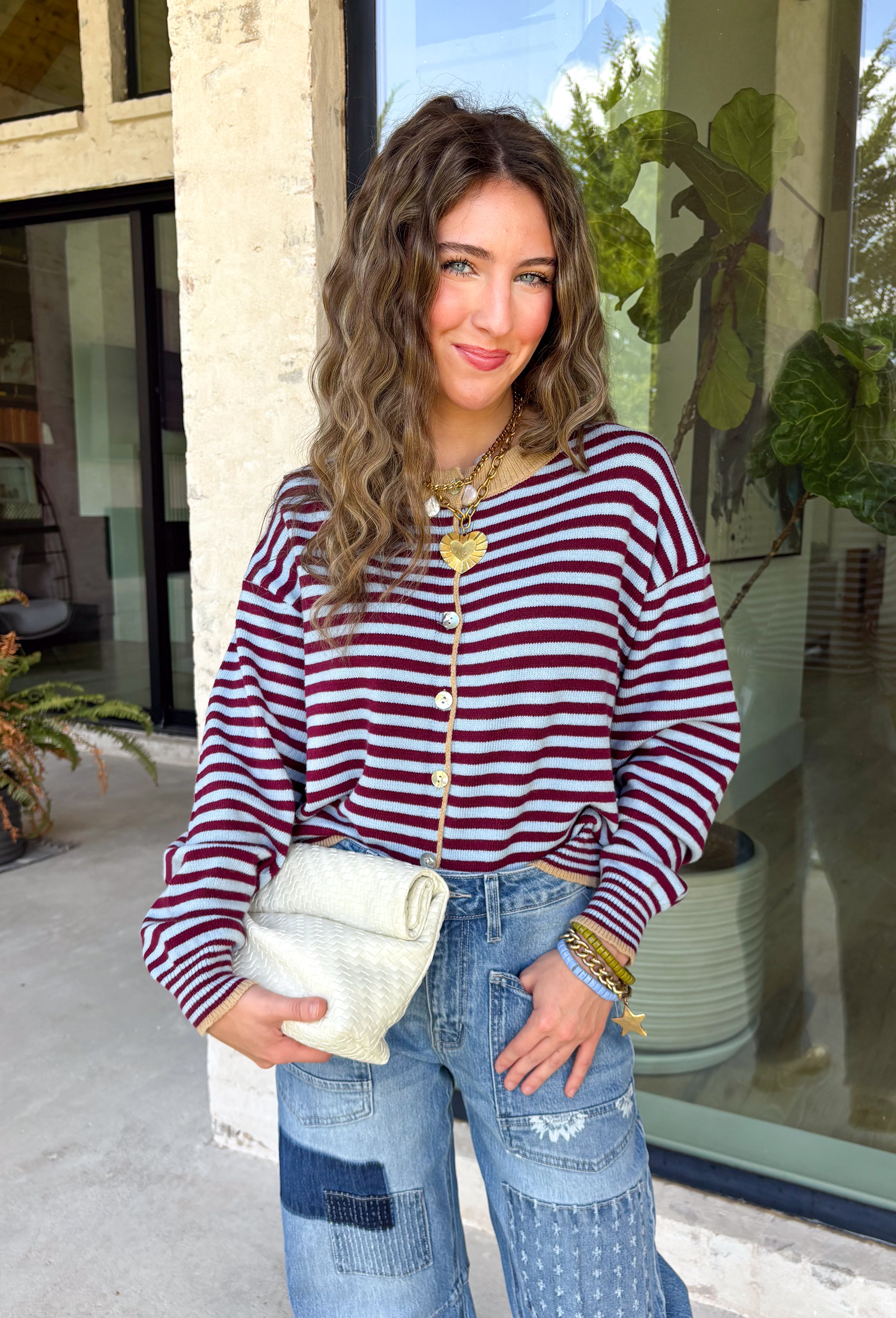 Rich fall colors come together beautifully in this cozy striped cardigan! Featuring burgundy and light blue stripes accented with warm tan trim, this timeless knit adds the perfect pop of seasonal color to any outfit. The button-down front offers endless styling options, while the ribbed neckline gives it a classic finish. Soft, lightweight, and easy to layer, this cardigan is perfect for everything from office days and coffee dates to football weekends and crisp autumn afternoons.
