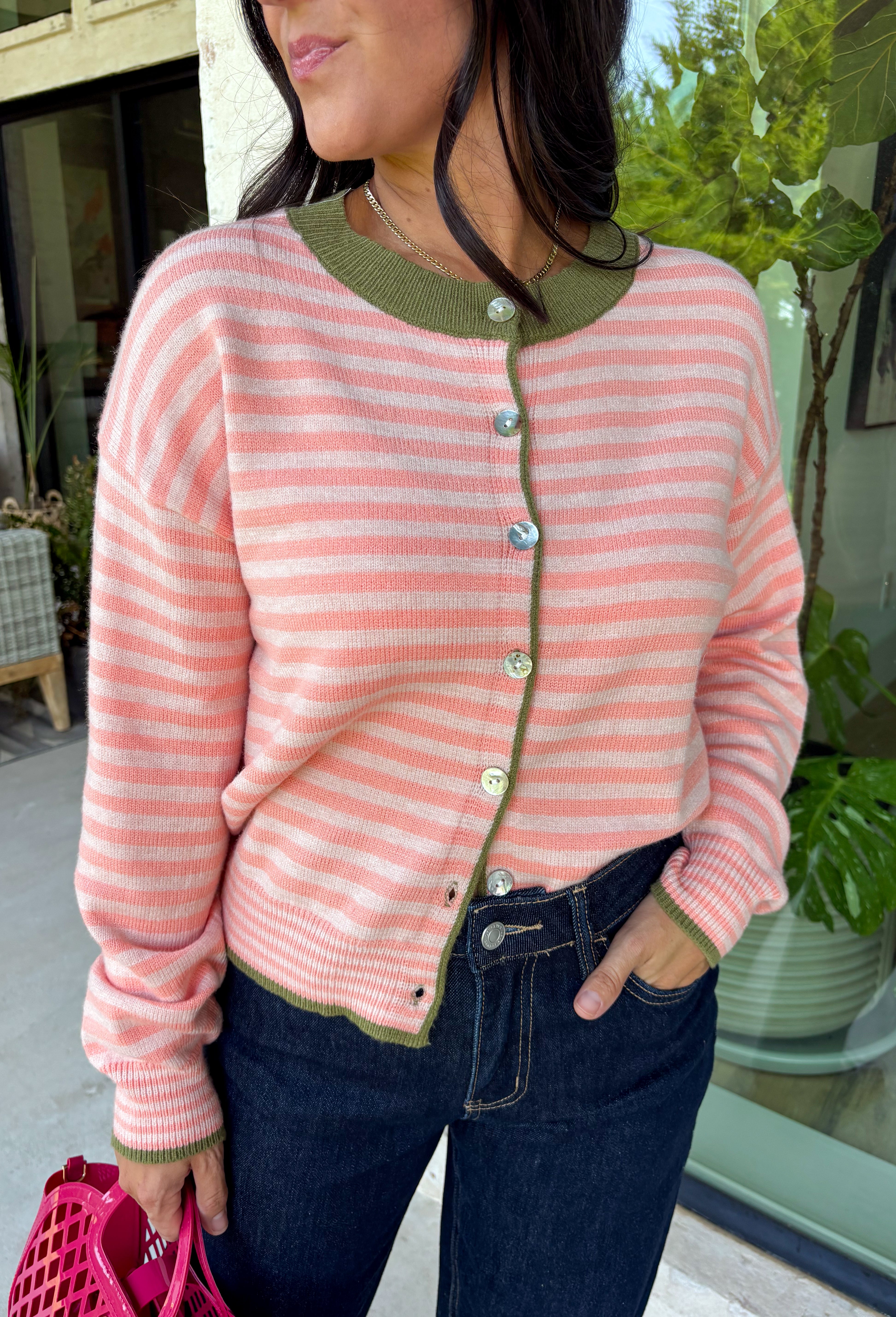 Bright colors come together beautifully in this cozy striped cardigan! Featuring pink and salmon stripes accented with an olive trim, this timeless knit adds the perfect pop of seasonal color to any outfit. The button-down front offers endless styling options, while the ribbed neckline gives it a classic finish. Soft, lightweight, and easy to layer, this cardigan is perfect for everything from office days and coffee dates to football weekends and crisp autumn afternoons.