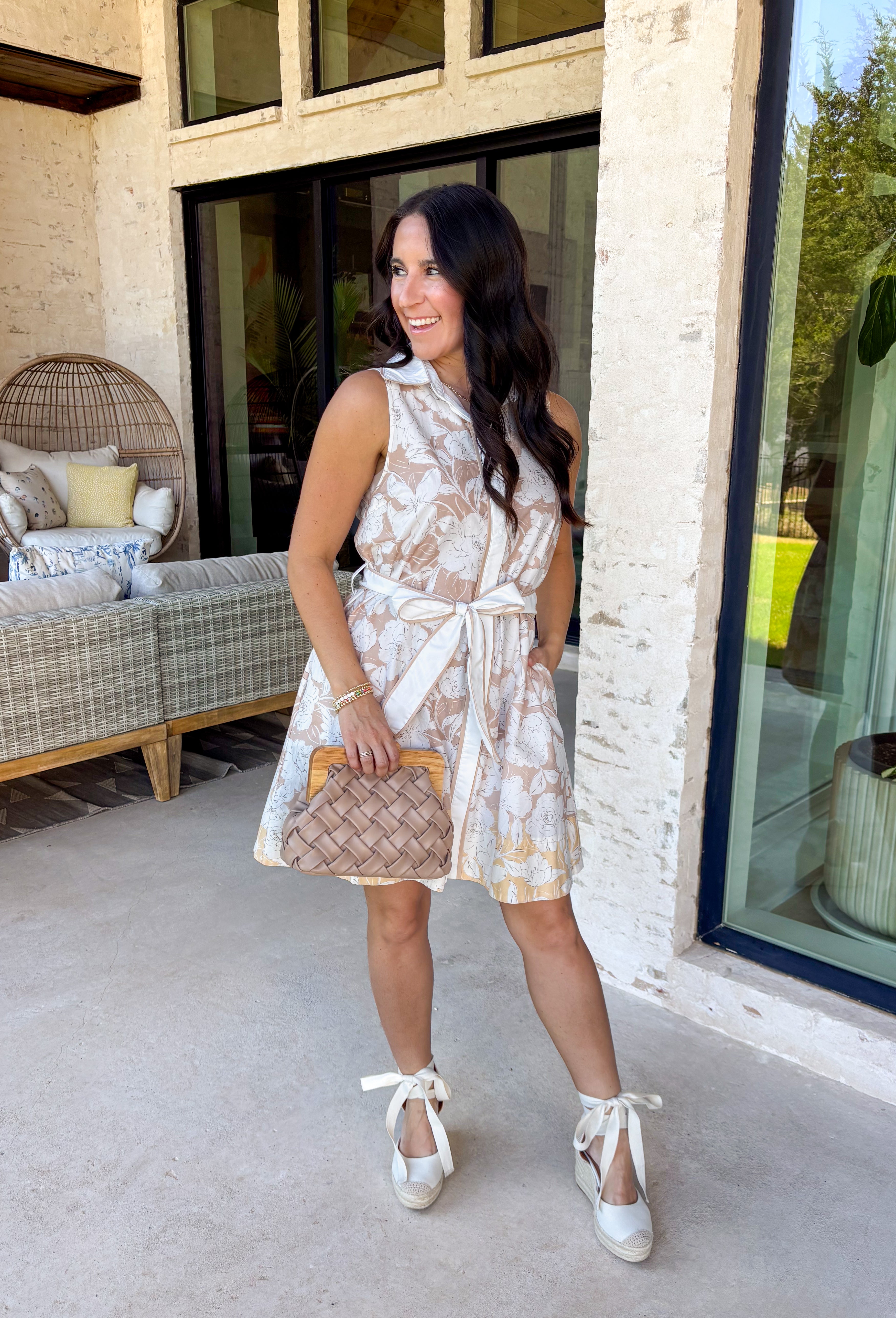 Soft, timeless, and perfect for spring days, this sleeveless tan dress is an effortless go-to for looking put together with minimal effort. Featuring a white floral print throughout, it has a fresh, neutral feel that’s easy to dress up or keep casual. The hidden button-down design and collared neckline give it a classic touch, while white trim along the front adds a clean contrast detail. 