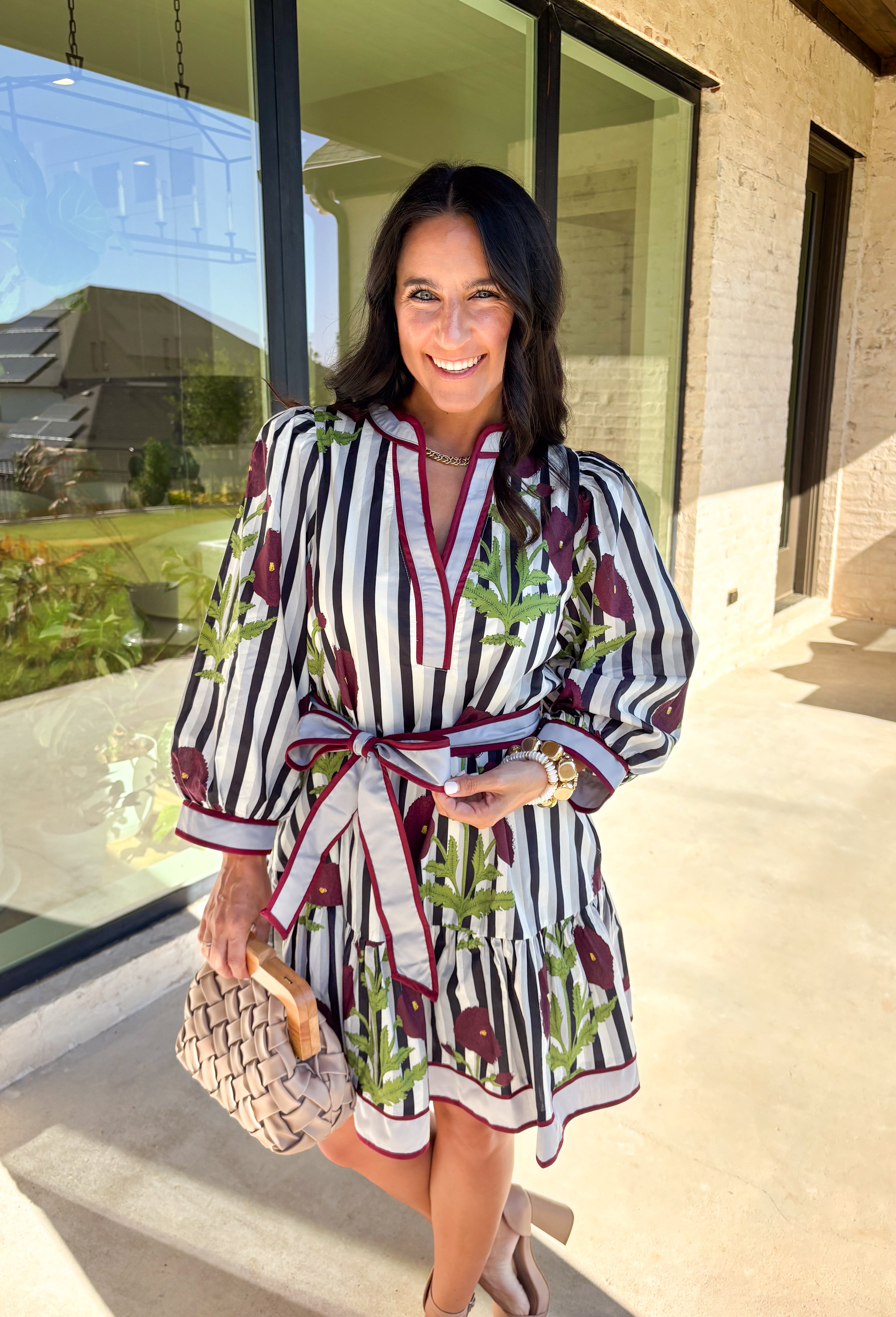 This floral stripe mini dress by Entro blends playful charm with seasonal flair. Featuring a gray, navy, light blue, off white and&nbsp; stripe base adorned with burgundy florals and green leaves, it’s the perfect balance of classic and bold. The ¾ puff sleeves add volume, while the v-neckline with contrast trim and adjustable self-tie belt create a flattering silhouette. A ruffle hem and side pockets finish the look, with a full cotton lining that makes it as practical as it is pretty.