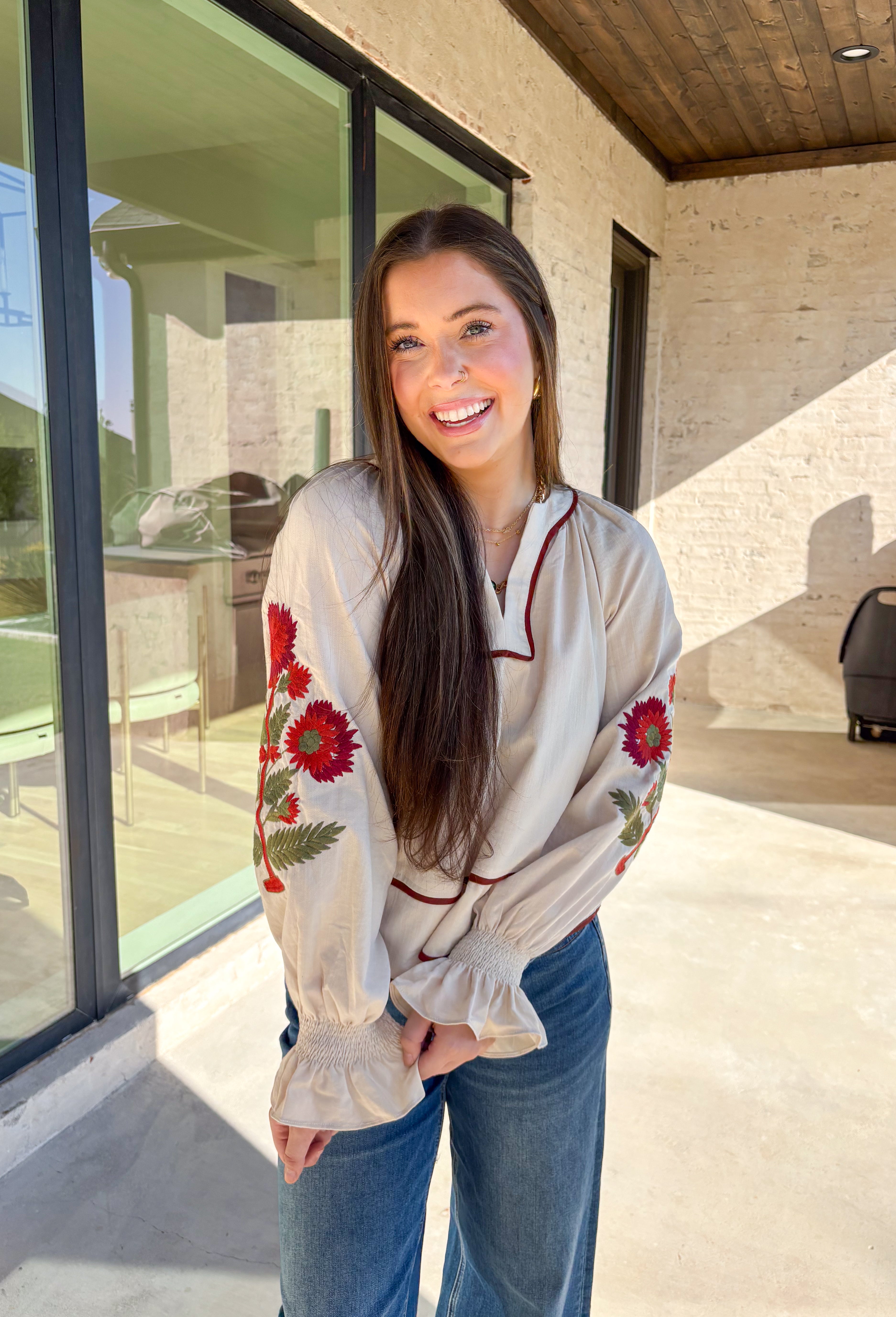 This ecru long sleeve top by Entro is the perfect blend of cozy neutrals and fall charm. Designed with puff sleeves and beautiful floral embroidery, it adds a soft, feminine touch to any outfit. The contrast piping at the neckline and waist gives it a flattering shape, while the smocked cuffs with ruffle edges add a sweet finishing detail. Effortless and chic, this top transitions perfectly from weekday wear to weekend outings.