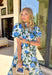 Soft, flowy, and full of spring romance, this off-white midi dress by Entro is an instant favorite. Featuring a beautiful green and blue floral print, it feels fresh and easy while still making a statement. The ruffled neckline and short puff sleeves add a sweet, feminine touch, while the button-front design keeps it classic and effortless. 