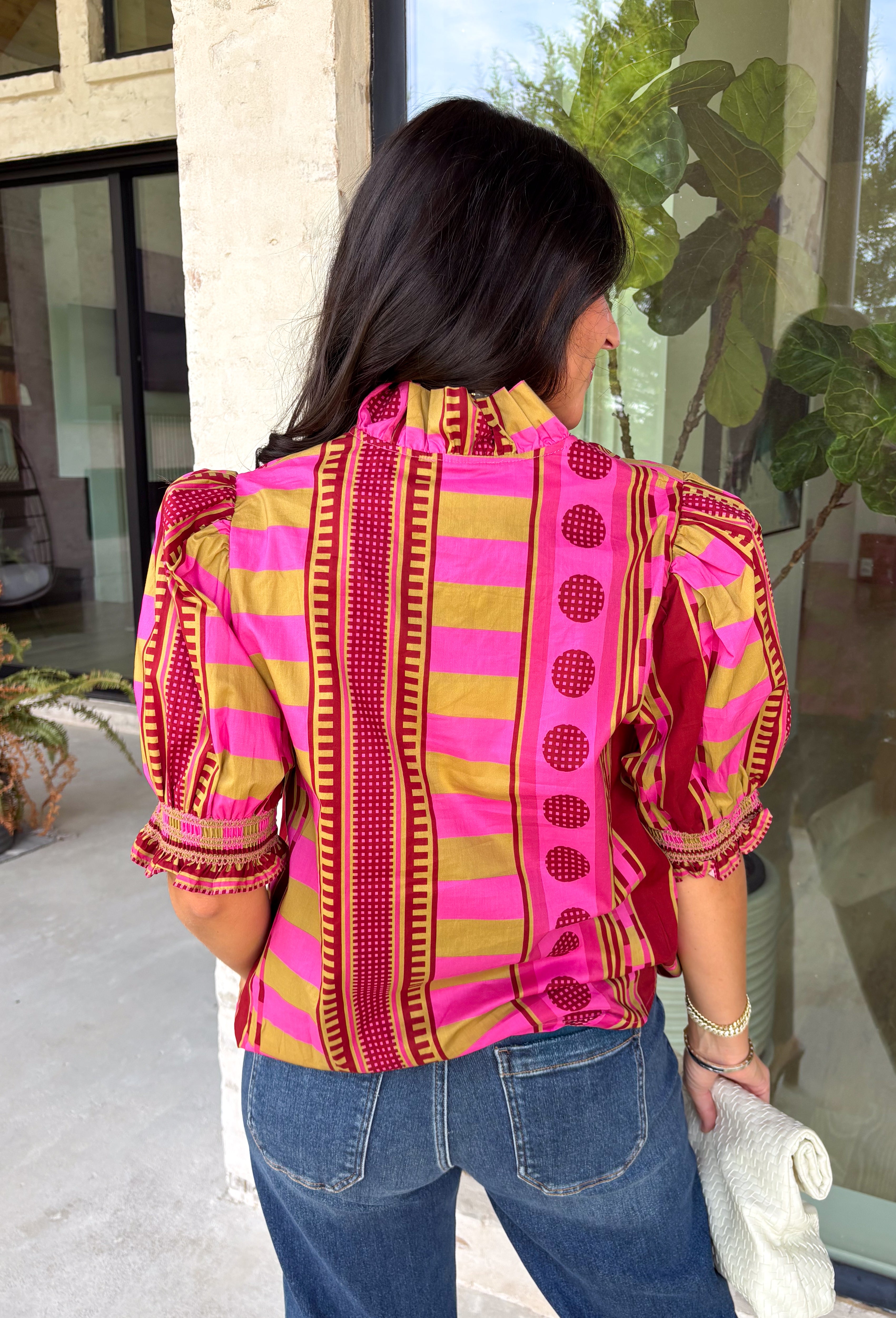 Bring playful pattern and timeless charm to your fall wardrobe with this beautifully detailed top from Entro. Featuring a unique mix of stripe and polka dot prints in rich shades of plum, magenta, and olive, this eye-catching blouse is perfect for adding personality to your everyday style. The feminine ruffle neckline and button-front design create a polished look, while the short puff sleeves are finished with smocked ruffle cuffs for an extra touch of charm. 