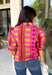Bring playful pattern and timeless charm to your fall wardrobe with this beautifully detailed top from Entro. Featuring a unique mix of stripe and polka dot prints in rich shades of plum, magenta, and olive, this eye-catching blouse is perfect for adding personality to your everyday style. The feminine ruffle neckline and button-front design create a polished look, while the short puff sleeves are finished with smocked ruffle cuffs for an extra touch of charm. 