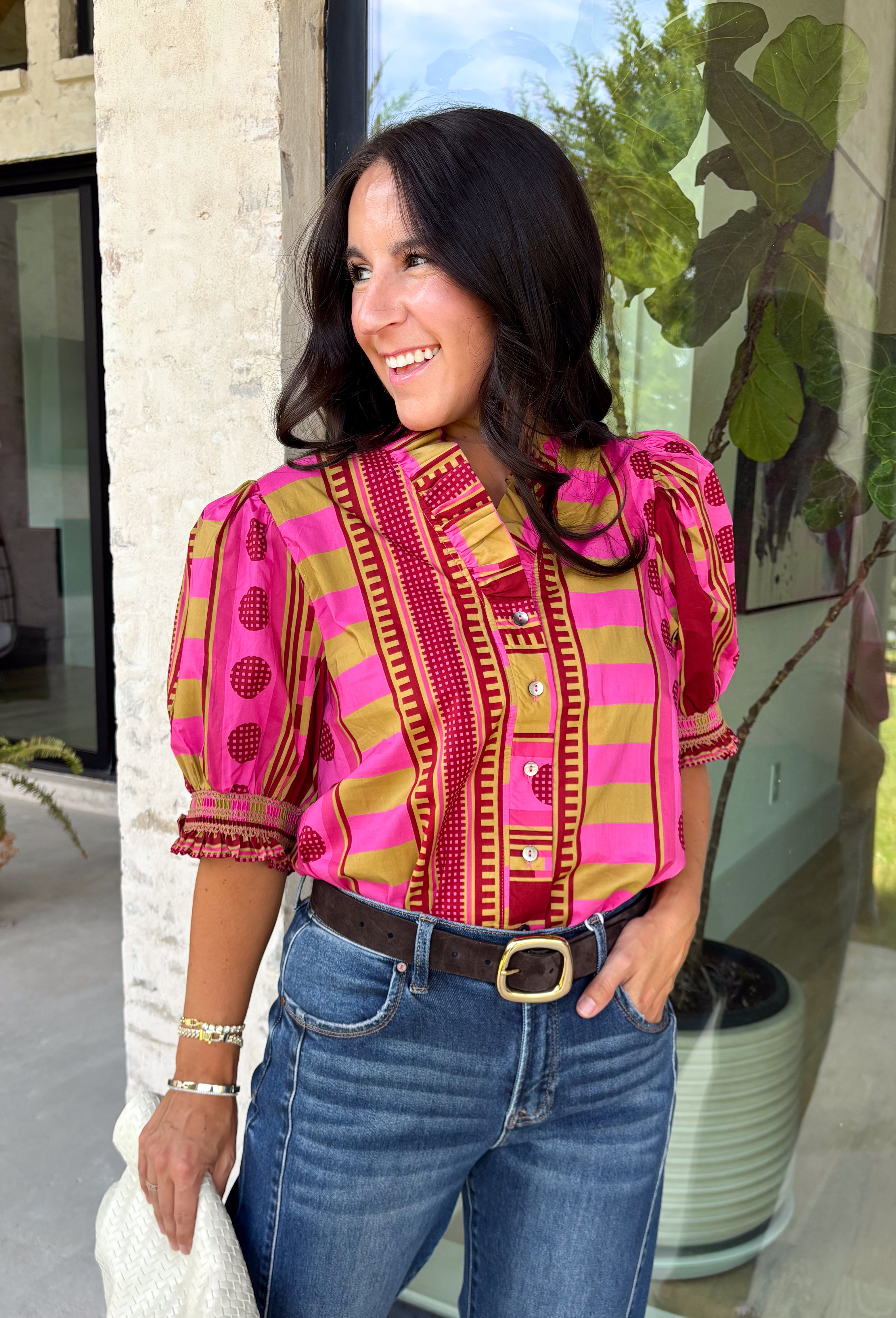 Bring playful pattern and timeless charm to your fall wardrobe with this beautifully detailed top from Entro. Featuring a unique mix of stripe and polka dot prints in rich shades of plum, magenta, and olive, this eye-catching blouse is perfect for adding personality to your everyday style. The feminine ruffle neckline and button-front design create a polished look, while the short puff sleeves are finished with smocked ruffle cuffs for an extra touch of charm. 