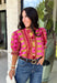Bring playful pattern and timeless charm to your fall wardrobe with this beautifully detailed top from Entro. Featuring a unique mix of stripe and polka dot prints in rich shades of plum, magenta, and olive, this eye-catching blouse is perfect for adding personality to your everyday style. The feminine ruffle neckline and button-front design create a polished look, while the short puff sleeves are finished with smocked ruffle cuffs for an extra touch of charm. 