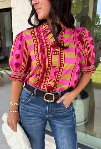 Bring playful pattern and timeless charm to your fall wardrobe with this beautifully detailed top from Entro. Featuring a unique mix of stripe and polka dot prints in rich shades of plum, magenta, and olive, this eye-catching blouse is perfect for adding personality to your everyday style. The feminine ruffle neckline and button-front design create a polished look, while the short puff sleeves are finished with smocked ruffle cuffs for an extra touch of charm. 