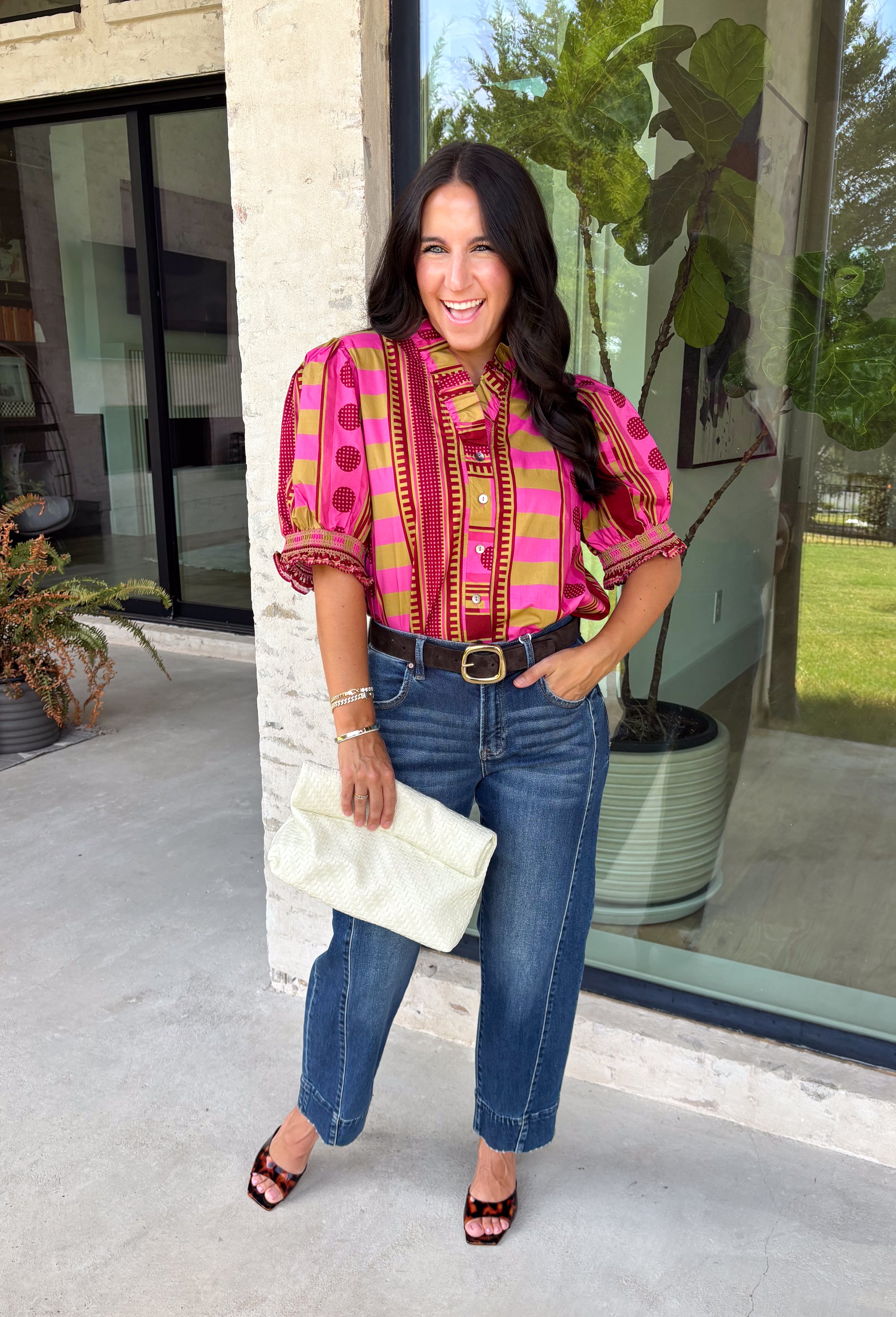 Bring playful pattern and timeless charm to your fall wardrobe with this beautifully detailed top from Entro. Featuring a unique mix of stripe and polka dot prints in rich shades of plum, magenta, and olive, this eye-catching blouse is perfect for adding personality to your everyday style. The feminine ruffle neckline and button-front design create a polished look, while the short puff sleeves are finished with smocked ruffle cuffs for an extra touch of charm. 