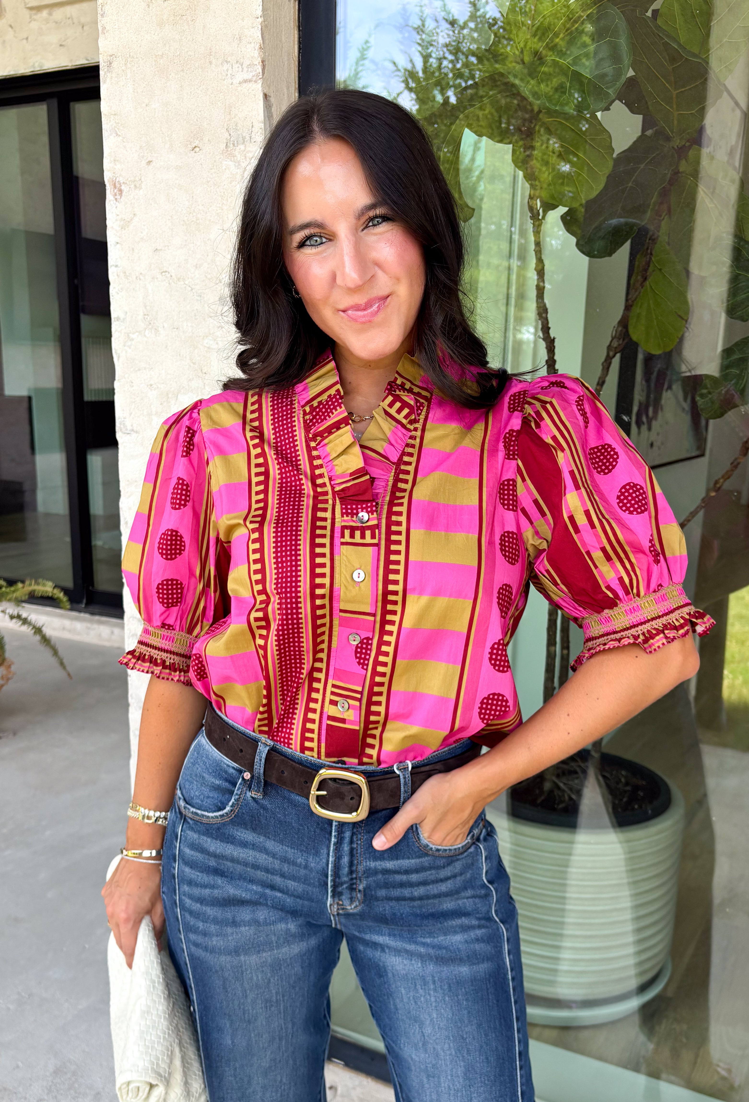 Bring playful pattern and timeless charm to your fall wardrobe with this beautifully detailed top from Entro. Featuring a unique mix of stripe and polka dot prints in rich shades of plum, magenta, and olive, this eye-catching blouse is perfect for adding personality to your everyday style. The feminine ruffle neckline and button-front design create a polished look, while the short puff sleeves are finished with smocked ruffle cuffs for an extra touch of charm. 