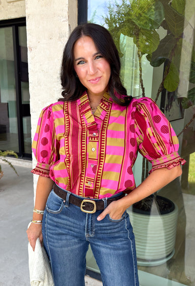 Bring playful pattern and timeless charm to your fall wardrobe with this beautifully detailed top from Entro. Featuring a unique mix of stripe and polka dot prints in rich shades of plum, magenta, and olive, this eye-catching blouse is perfect for adding personality to your everyday style. The feminine ruffle neckline and button-front design create a polished look, while the short puff sleeves are finished with smocked ruffle cuffs for an extra touch of charm. 