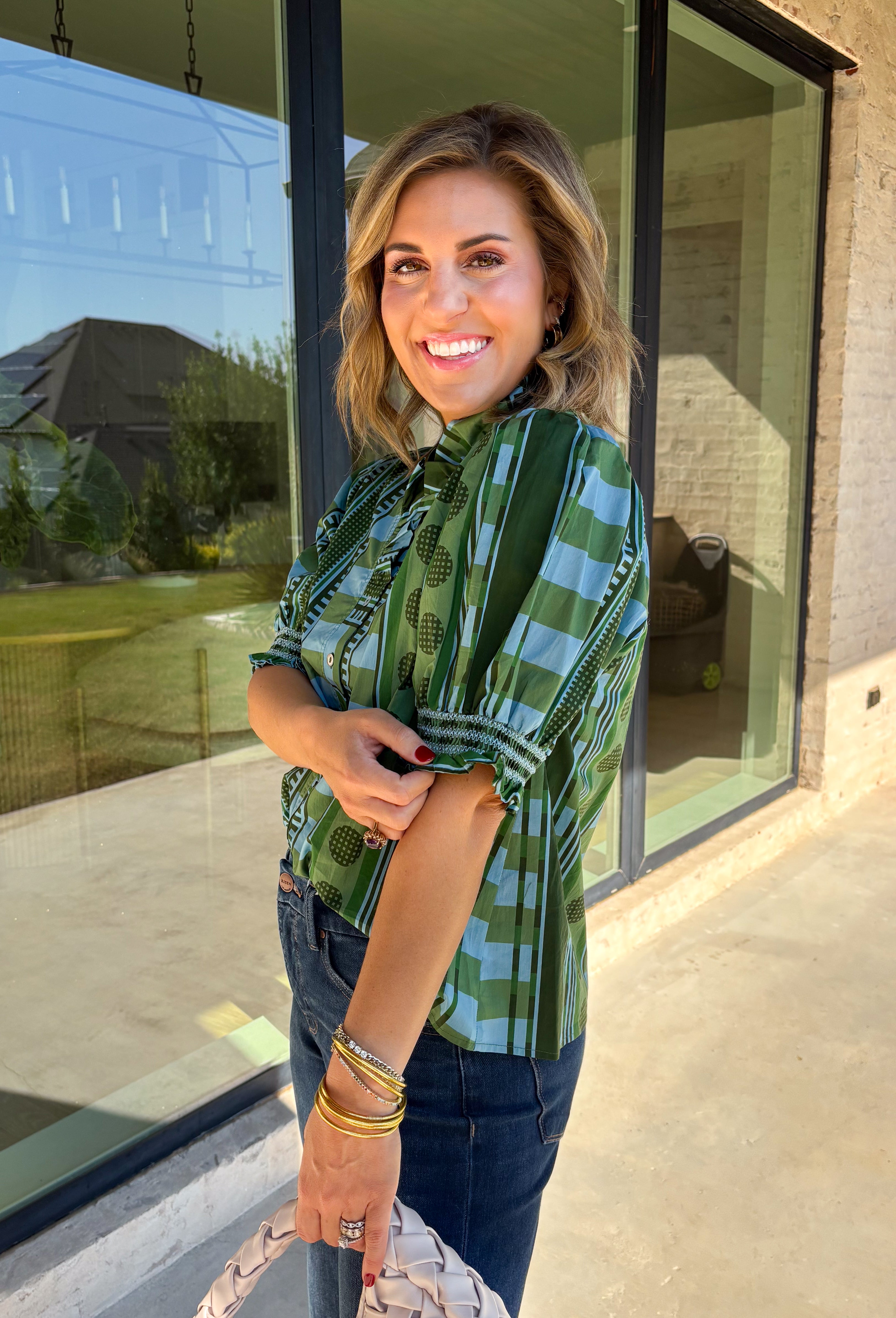 Bring playful pattern and timeless charm to your fall wardrobe with this beautifully detailed top from Entro. Featuring a unique mix of stripe and polka dot prints in rich shades of olive and blue, this eye-catching blouse is perfect for adding personality to your everyday style. The feminine ruffle neckline and button-front design create a polished look, while the short puff sleeves are finished with smocked ruffle cuffs for an extra touch of charm. 