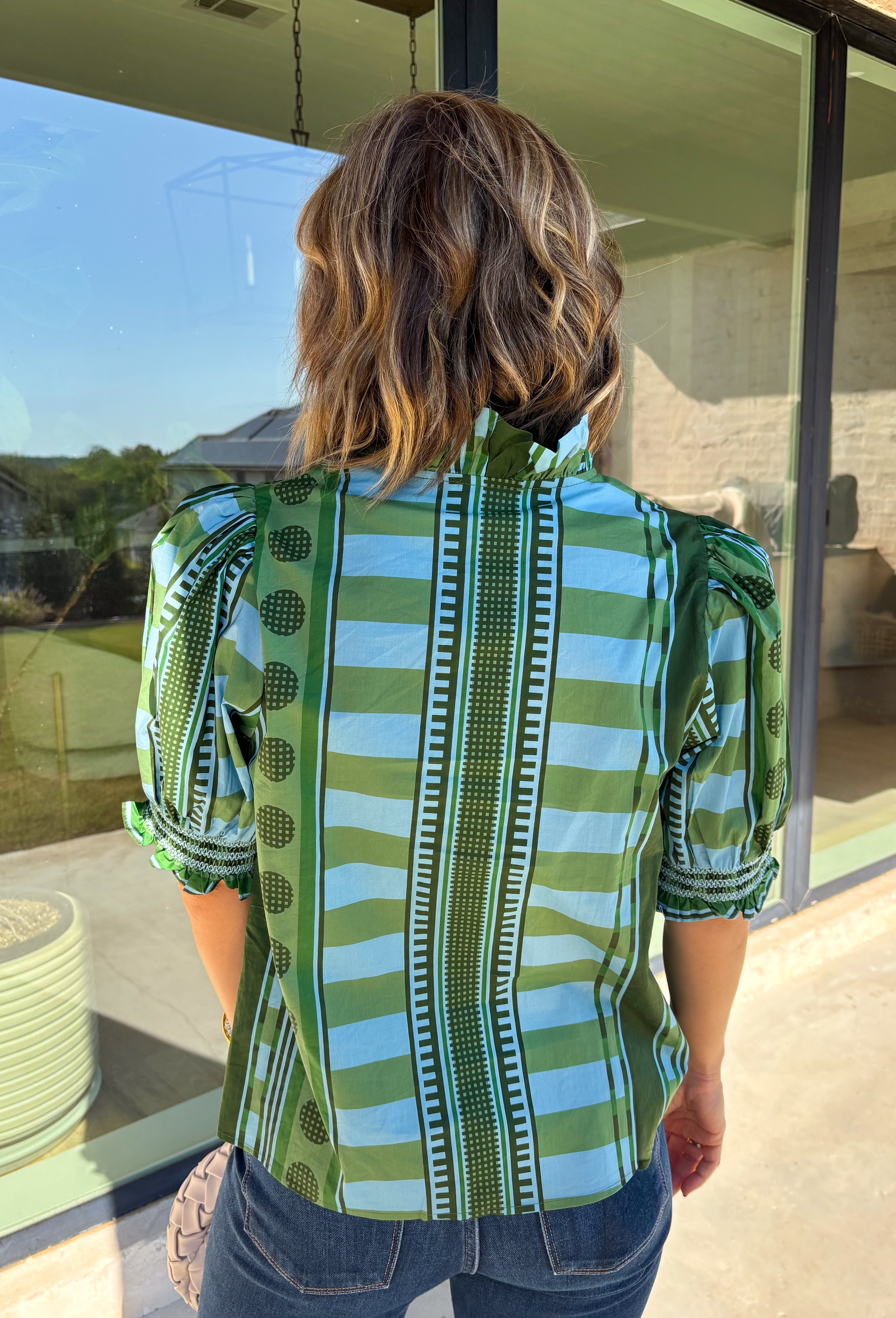Bring playful pattern and timeless charm to your fall wardrobe with this beautifully detailed top from Entro. Featuring a unique mix of stripe and polka dot prints in rich shades of olive and blue, this eye-catching blouse is perfect for adding personality to your everyday style. The feminine ruffle neckline and button-front design create a polished look, while the short puff sleeves are finished with smocked ruffle cuffs for an extra touch of charm. 