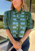Bring playful pattern and timeless charm to your fall wardrobe with this beautifully detailed top from Entro. Featuring a unique mix of stripe and polka dot prints in rich shades of olive and blue, this eye-catching blouse is perfect for adding personality to your everyday style. The feminine ruffle neckline and button-front design create a polished look, while the short puff sleeves are finished with smocked ruffle cuffs for an extra touch of charm. 