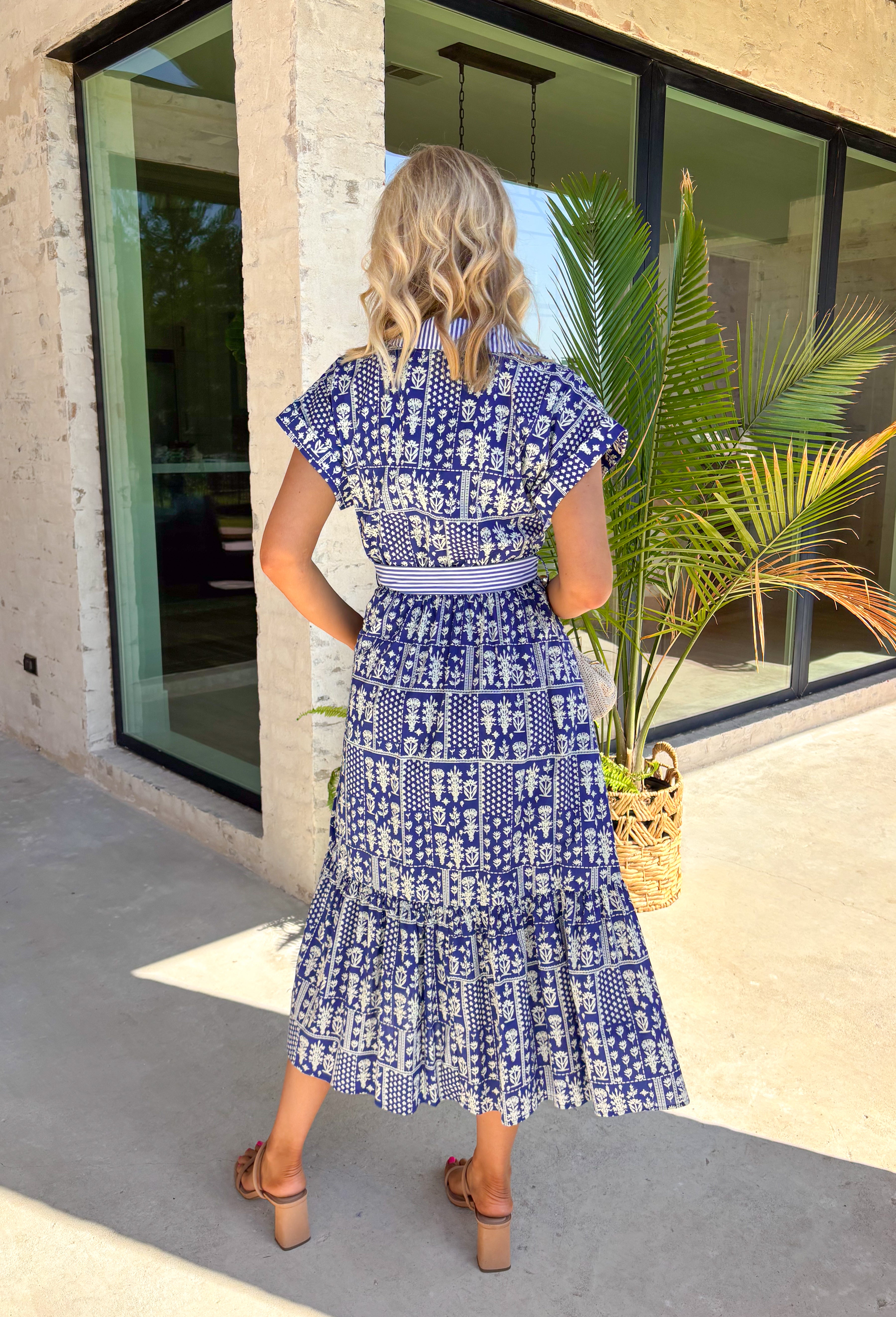Fresh, charming, and full of thoughtful details, this blue button-down midi dress by Entro feels like spring in dress form. Featuring an off-white floral print with delicate mini star accents throughout, it strikes the perfect balance between playful and classic. The blue and white striped collar and trim add a crisp contrast, while the matching self-tie waist creates a flattering, easy fit. 
