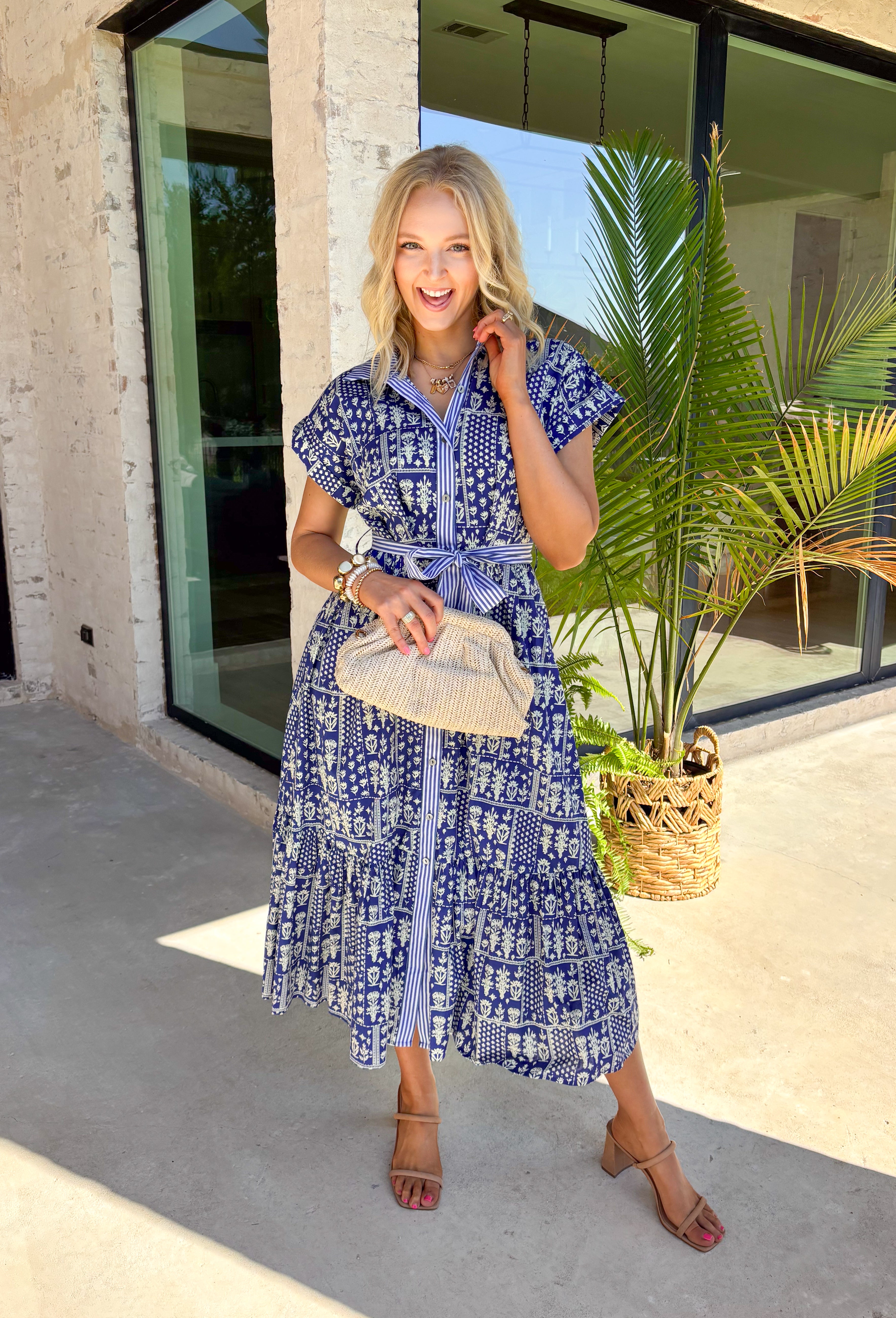 Fresh, charming, and full of thoughtful details, this blue button-down midi dress by Entro feels like spring in dress form. Featuring an off-white floral print with delicate mini star accents throughout, it strikes the perfect balance between playful and classic. The blue and white striped collar and trim add a crisp contrast, while the matching self-tie waist creates a flattering, easy fit. 