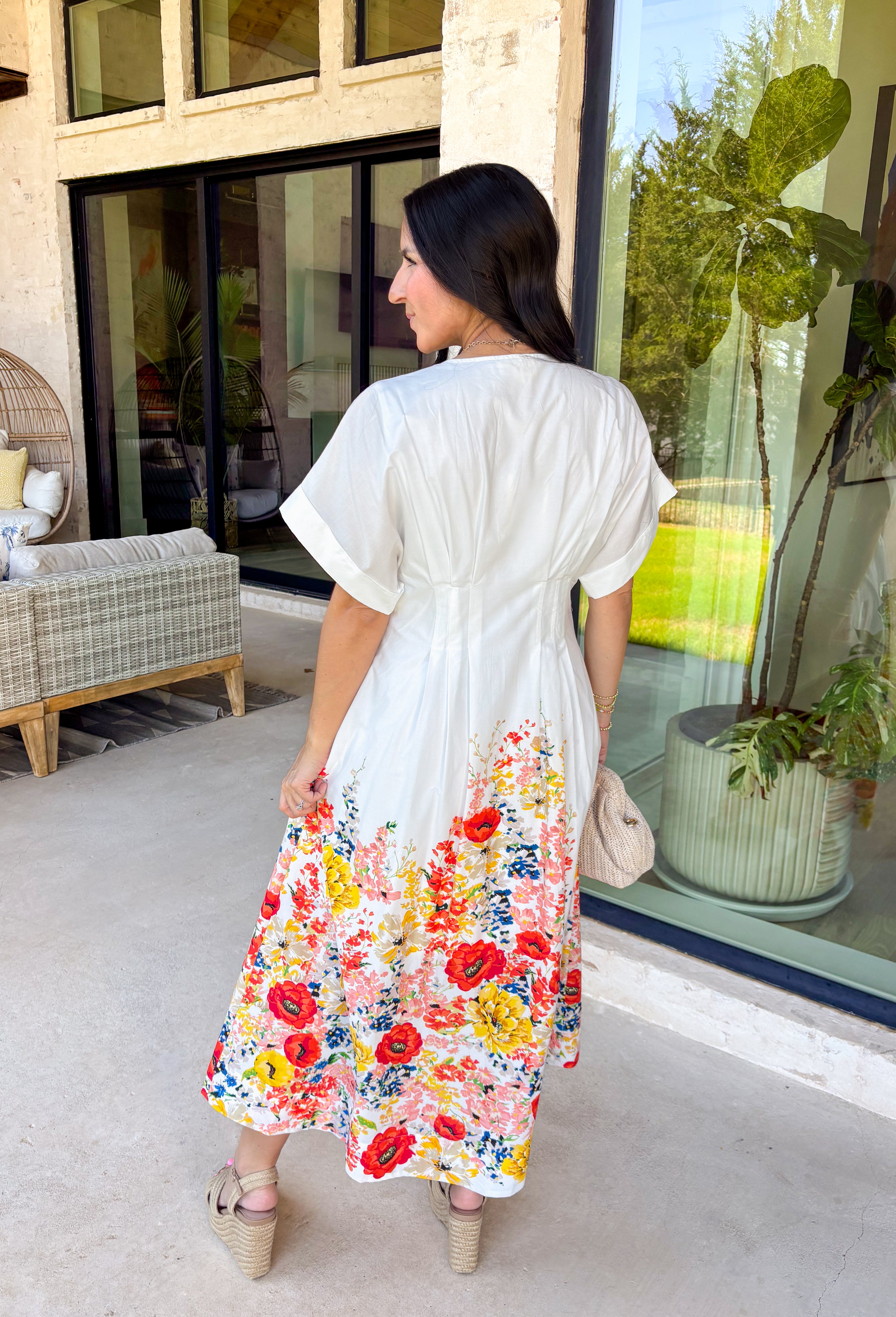 Fresh, timeless, and full of spring color, this white button-down midi dress by Entro is an instant favorite. The clean white base keeps it classic, while the colorful floral print along the bottom adds the prettiest pop of color—featuring shades of orange, red, yellow, pink, blue, and green. Cuffed sleeves give it an easy, relaxed feel, and pleating detail along the front adds a flattering touch that elevates the whole look. 