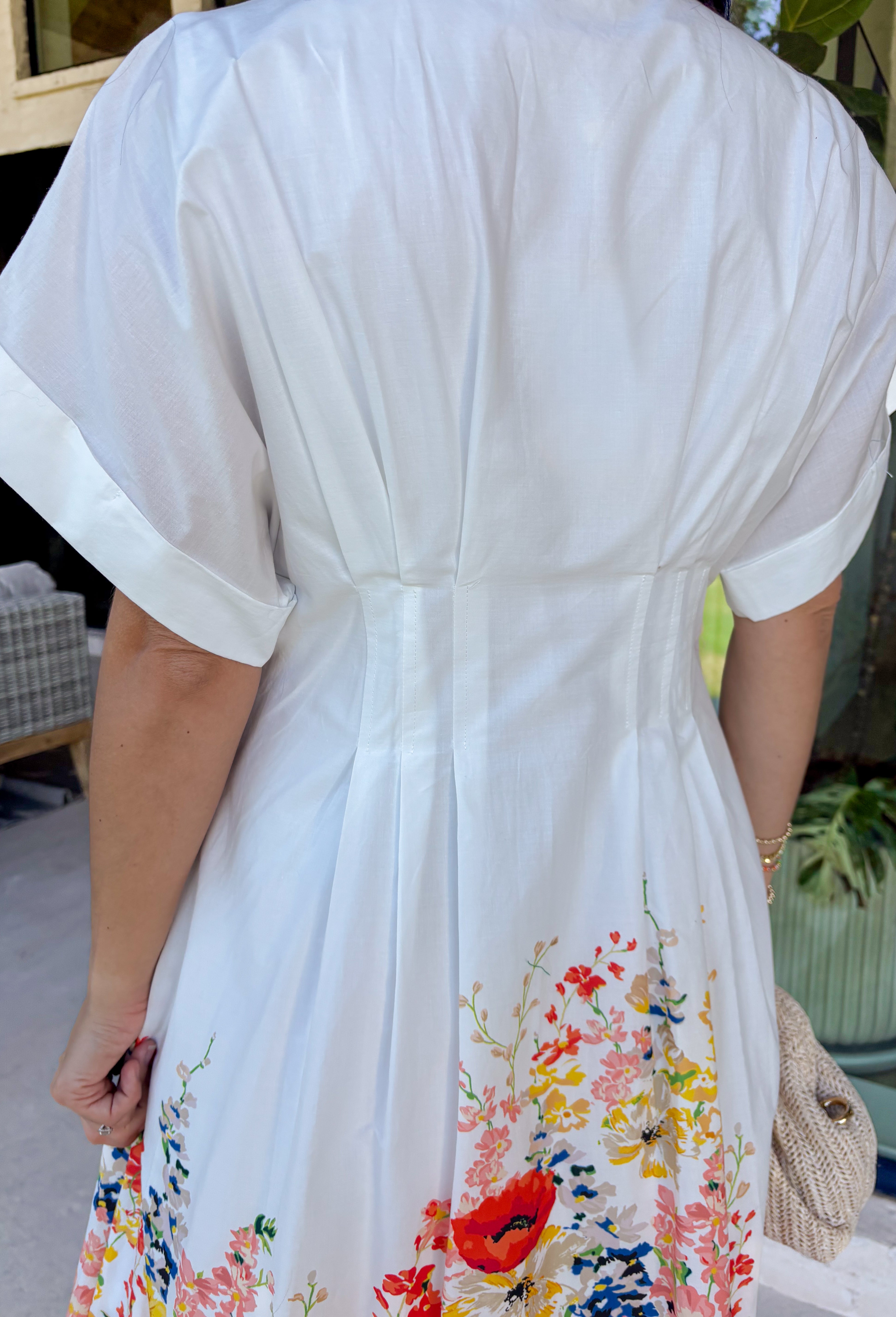Fresh, timeless, and full of spring color, this white button-down midi dress by Entro is an instant favorite. The clean white base keeps it classic, while the colorful floral print along the bottom adds the prettiest pop of color—featuring shades of orange, red, yellow, pink, blue, and green. Cuffed sleeves give it an easy, relaxed feel, and pleating detail along the front adds a flattering touch that elevates the whole look. 