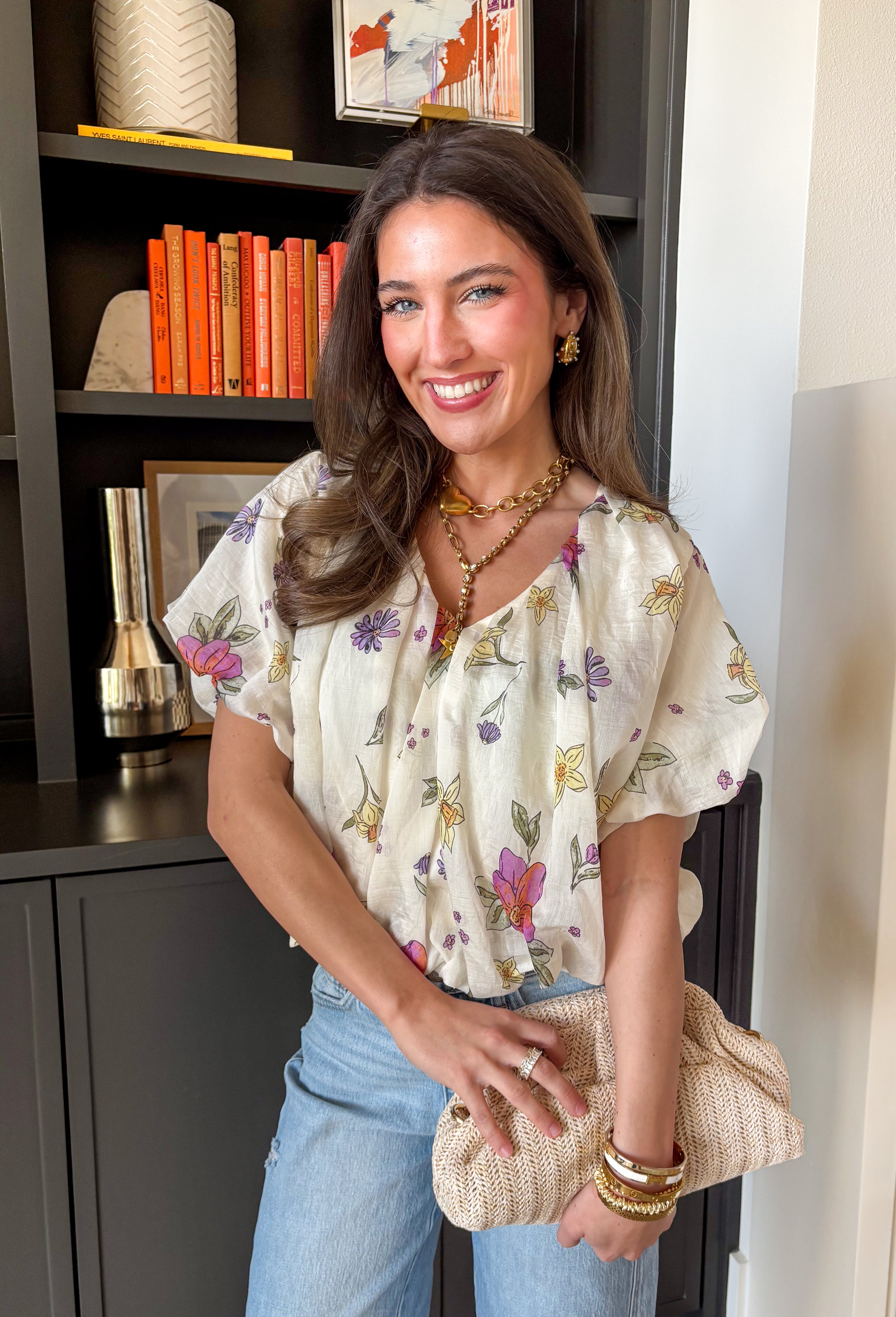 Bright, breezy, and full of spring color, this cream short sleeve top by Entro is an instant mood booster. Featuring a colorful floral print with pops of purple, orange, yellow, and green, it adds the perfect playful touch to your everyday look. Puff sleeves with elastic cuffs give it a sweet, feminine shape, while the elastic hem creates an easy, flattering fit that pairs perfectly with high-rise denim. Made from a lightweight tencel blend, it feels soft, airy, and effortlessly comfortable.
