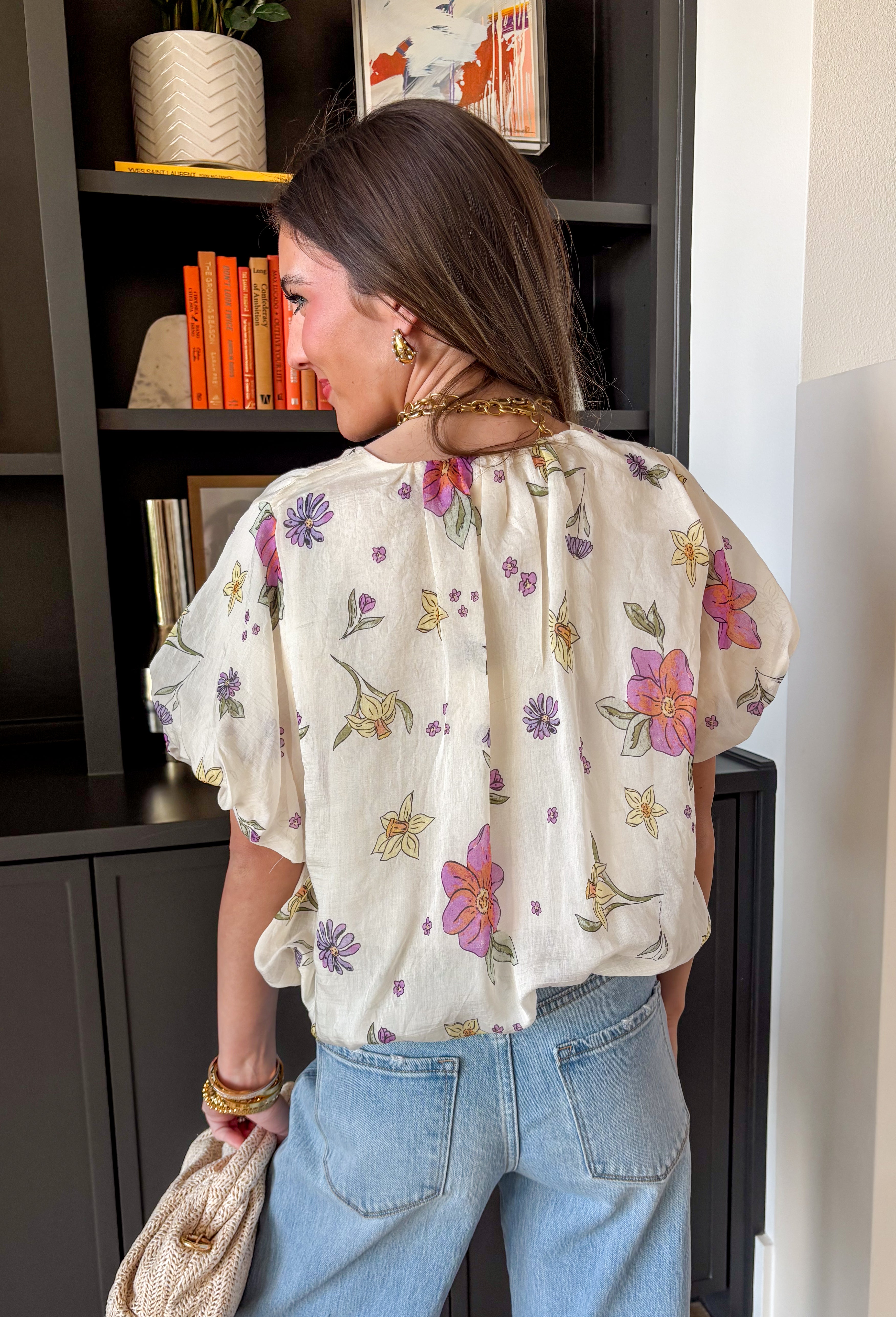 Bright, breezy, and full of spring color, this cream short sleeve top by Entro is an instant mood booster. Featuring a colorful floral print with pops of purple, orange, yellow, and green, it adds the perfect playful touch to your everyday look. Puff sleeves with elastic cuffs give it a sweet, feminine shape, while the elastic hem creates an easy, flattering fit that pairs perfectly with high-rise denim. Made from a lightweight tencel blend, it feels soft, airy, and effortlessly comfortable.