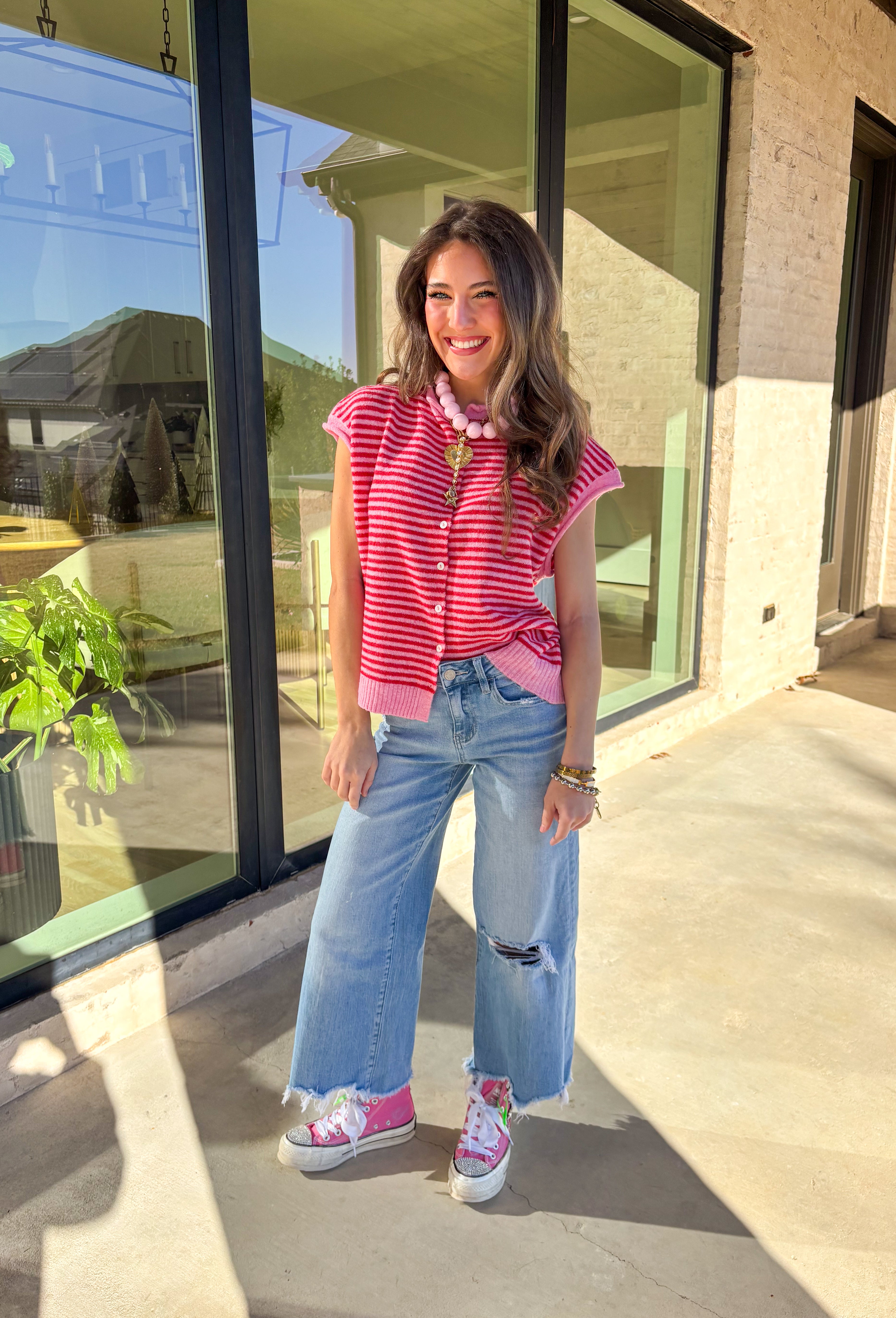 Bright, cheerful, and perfect for spring layering, this red and pink striped sleeveless button-down cardigan by Things Between is a fun statement piece. Designed in a sweater vest cardigan style, it features bold stripes and a rolled hem detail that gives it a relaxed, effortless feel. Lightweight with just the right amount of warmth, it’s ideal for layering over tees, tanks, or dresses as the seasons change.