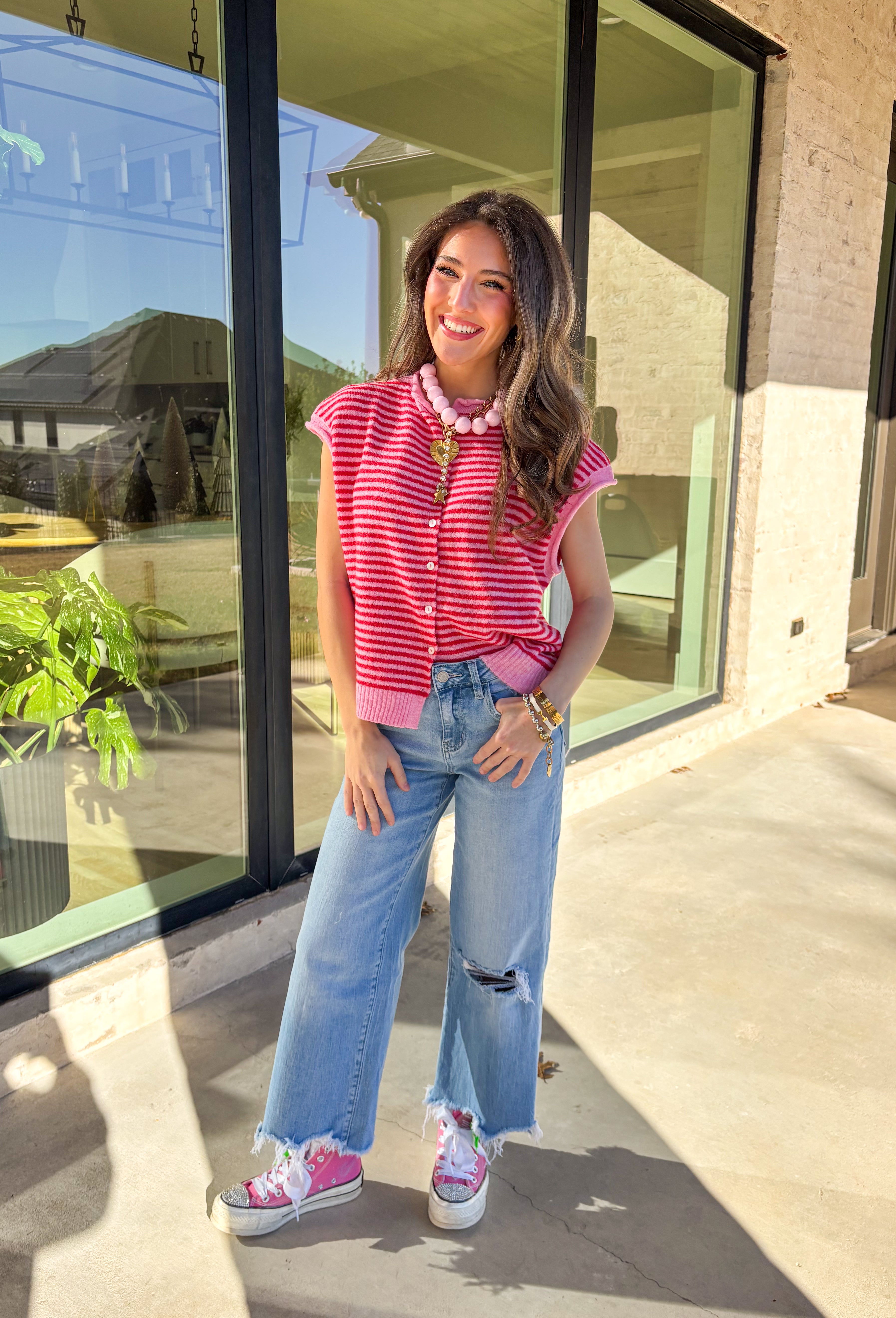 Bright, cheerful, and perfect for spring layering, this red and pink striped sleeveless button-down cardigan by Things Between is a fun statement piece. Designed in a sweater vest cardigan style, it features bold stripes and a rolled hem detail that gives it a relaxed, effortless feel. Lightweight with just the right amount of warmth, it’s ideal for layering over tees, tanks, or dresses as the seasons change.