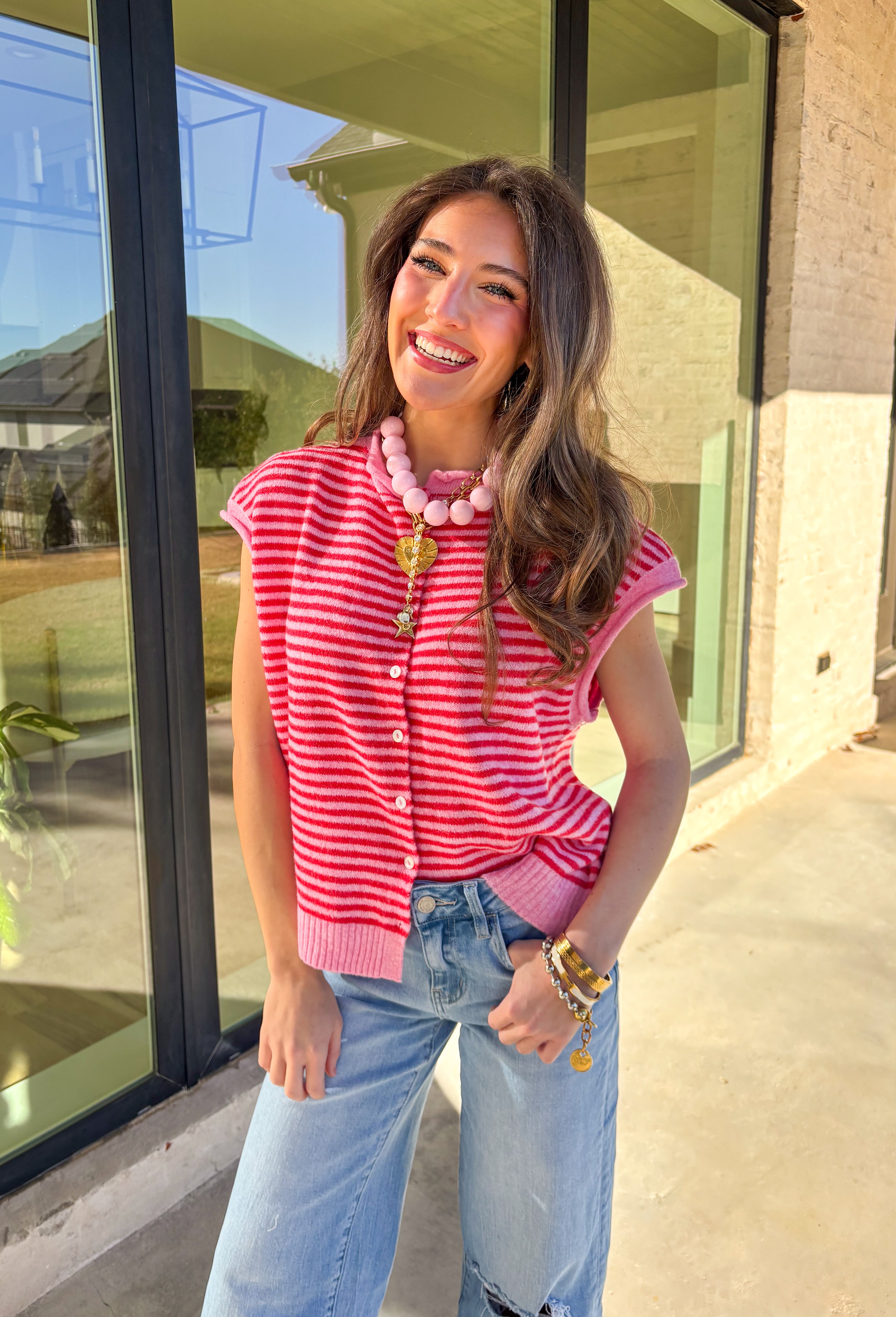 Bright, cheerful, and perfect for spring layering, this red and pink striped sleeveless button-down cardigan by Things Between is a fun statement piece. Designed in a sweater vest cardigan style, it features bold stripes and a rolled hem detail that gives it a relaxed, effortless feel. Lightweight with just the right amount of warmth, it’s ideal for layering over tees, tanks, or dresses as the seasons change.