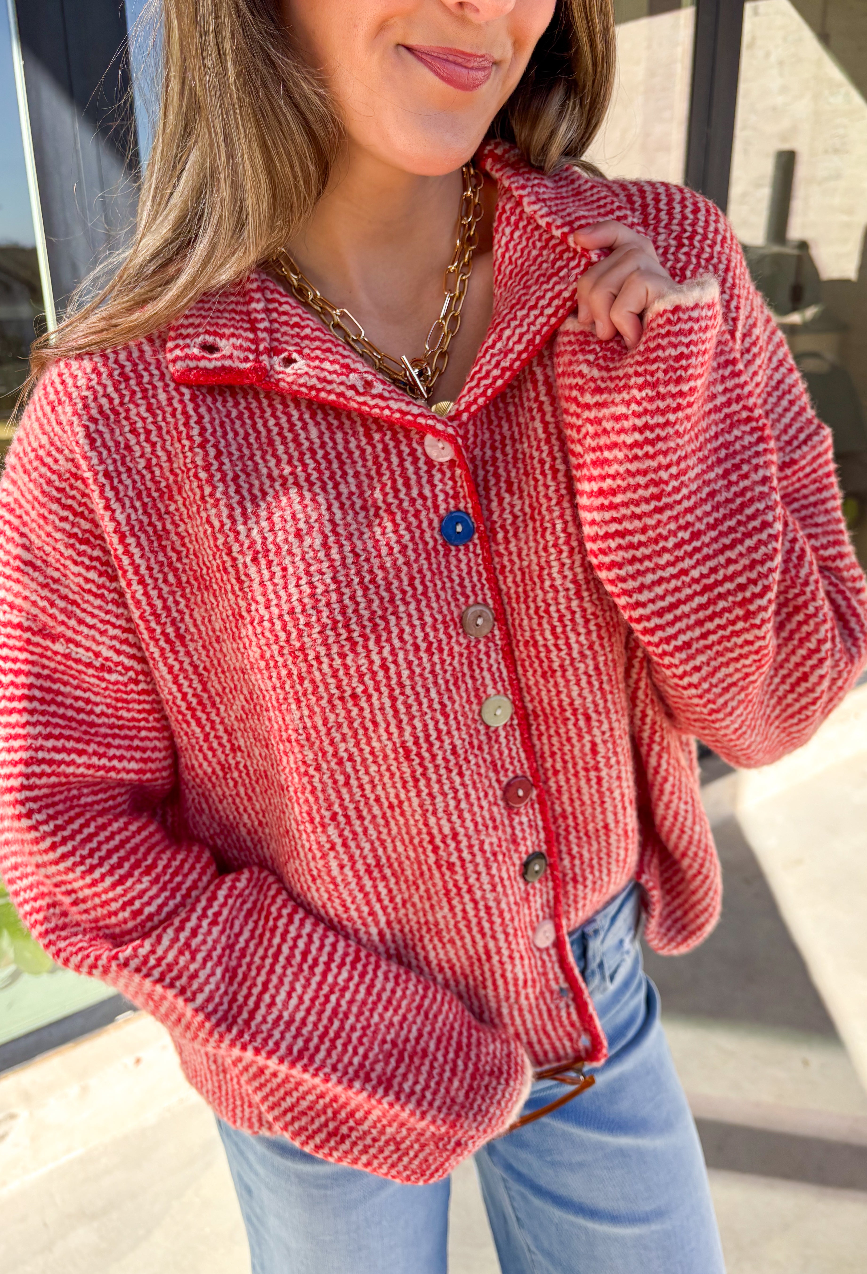 Cozy meets classic in this red and white mini chevron knit cardigan by &amp;Merci. Designed with a mock neck and colorful button-down front, this sweater brings a fun twist to a timeless winter look. The soft knit texture and warm tones make it the perfect layer for chilly days!