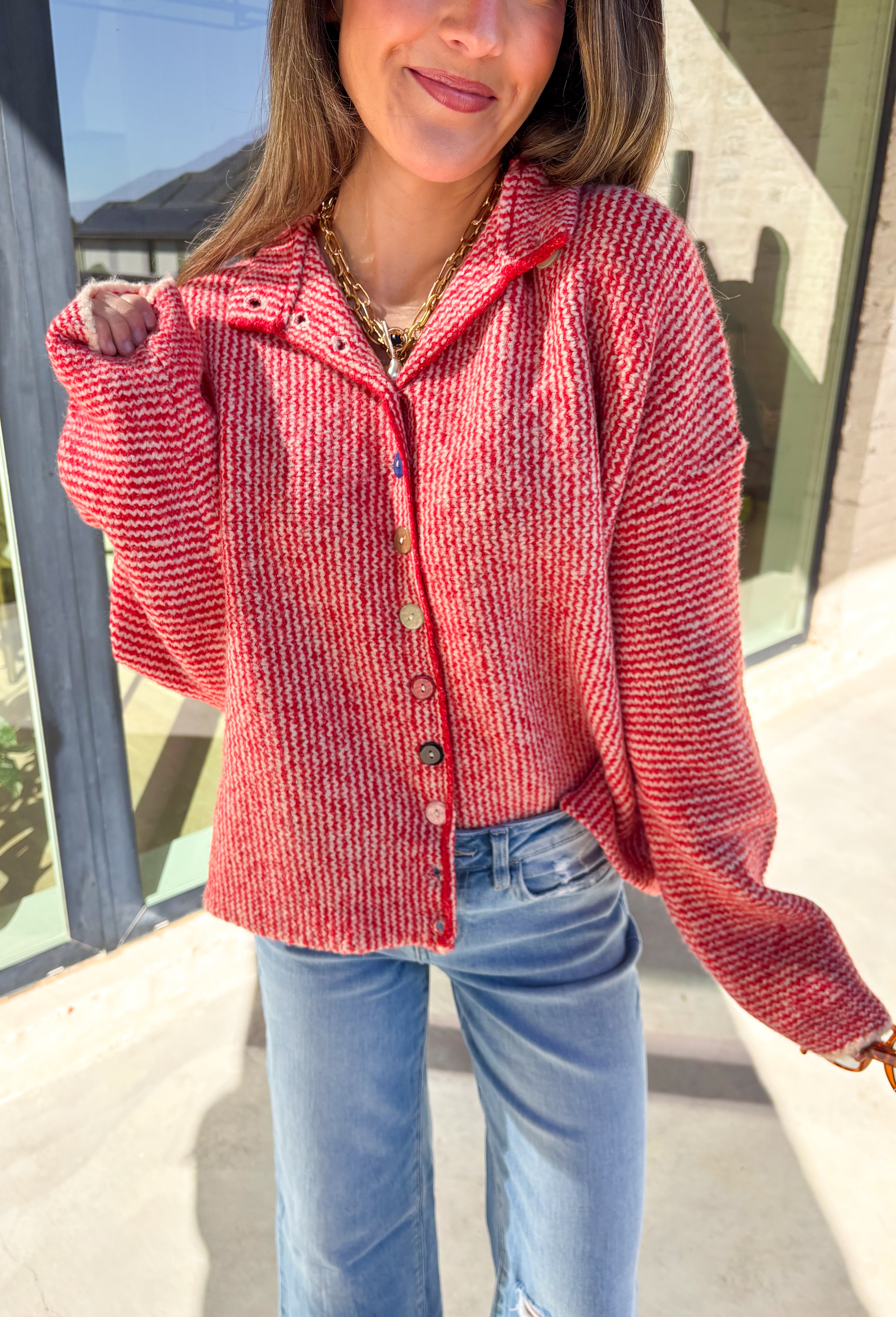 Cozy meets classic in this red and white mini chevron knit cardigan by &amp;Merci. Designed with a mock neck and colorful button-down front, this sweater brings a fun twist to a timeless winter look. The soft knit texture and warm tones make it the perfect layer for chilly days!