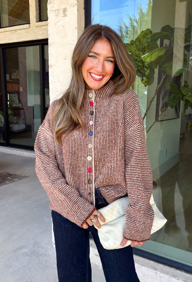 Cozy meets classic in this brown and taupe mini chevron knit cardigan by &Merci. The playful chevron pattern gives this sweater a fun, vintage-inspired feel, while the colorful button-down front adds an unexpected pop of personality. Designed with a mock neckline and a soft, cozy knit texture, it’s perfect for keeping warm when the temperatures start to drop. The classic brown and taupe color combination makes it an easy choice for winter days, holiday outings, and casual weekends. 
