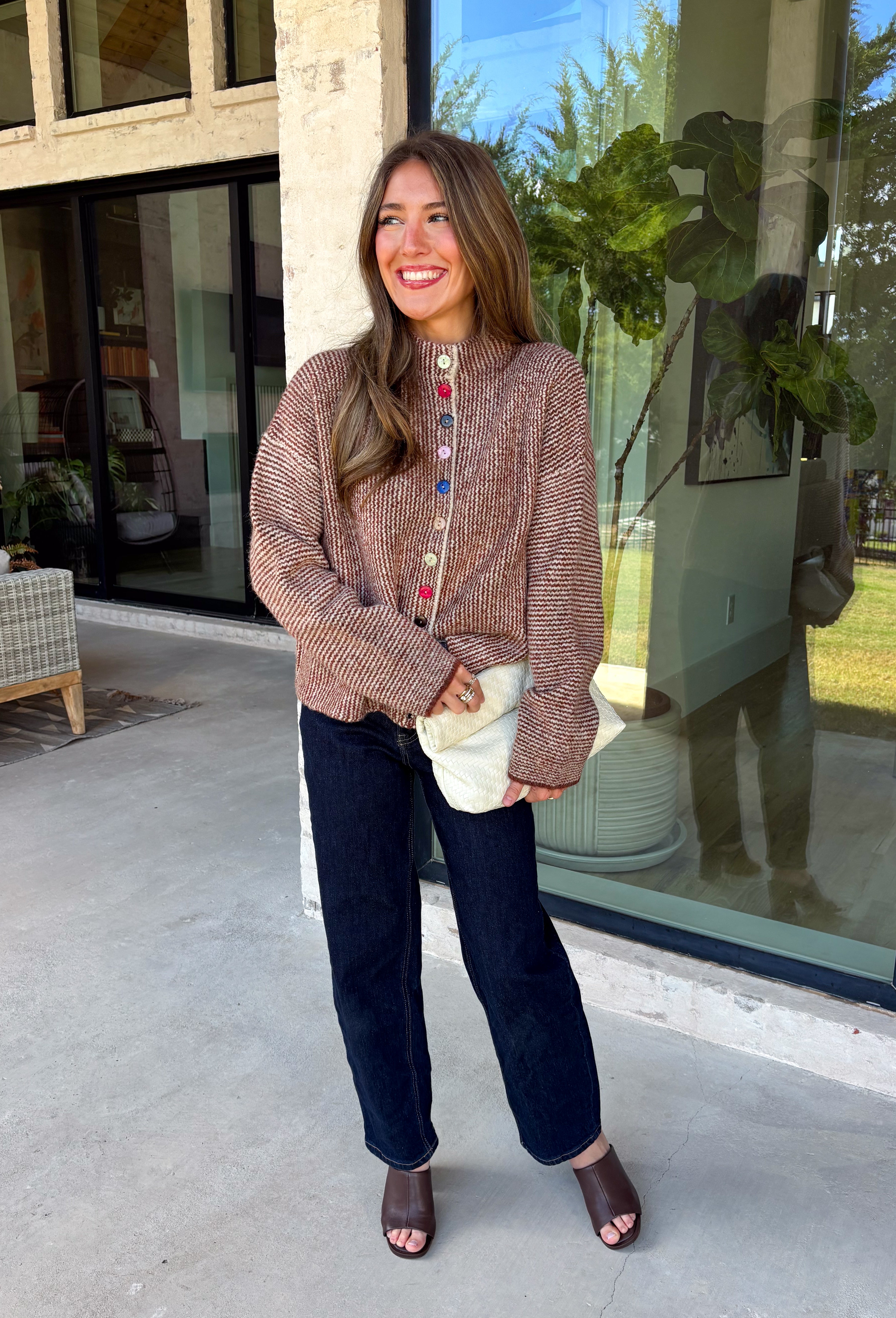 Cozy meets classic in this brown and taupe mini chevron knit cardigan by &Merci. The playful chevron pattern gives this sweater a fun, vintage-inspired feel, while the colorful button-down front adds an unexpected pop of personality. Designed with a mock neckline and a soft, cozy knit texture, it’s perfect for keeping warm when the temperatures start to drop. The classic brown and taupe color combination makes it an easy choice for winter days, holiday outings, and casual weekends. 