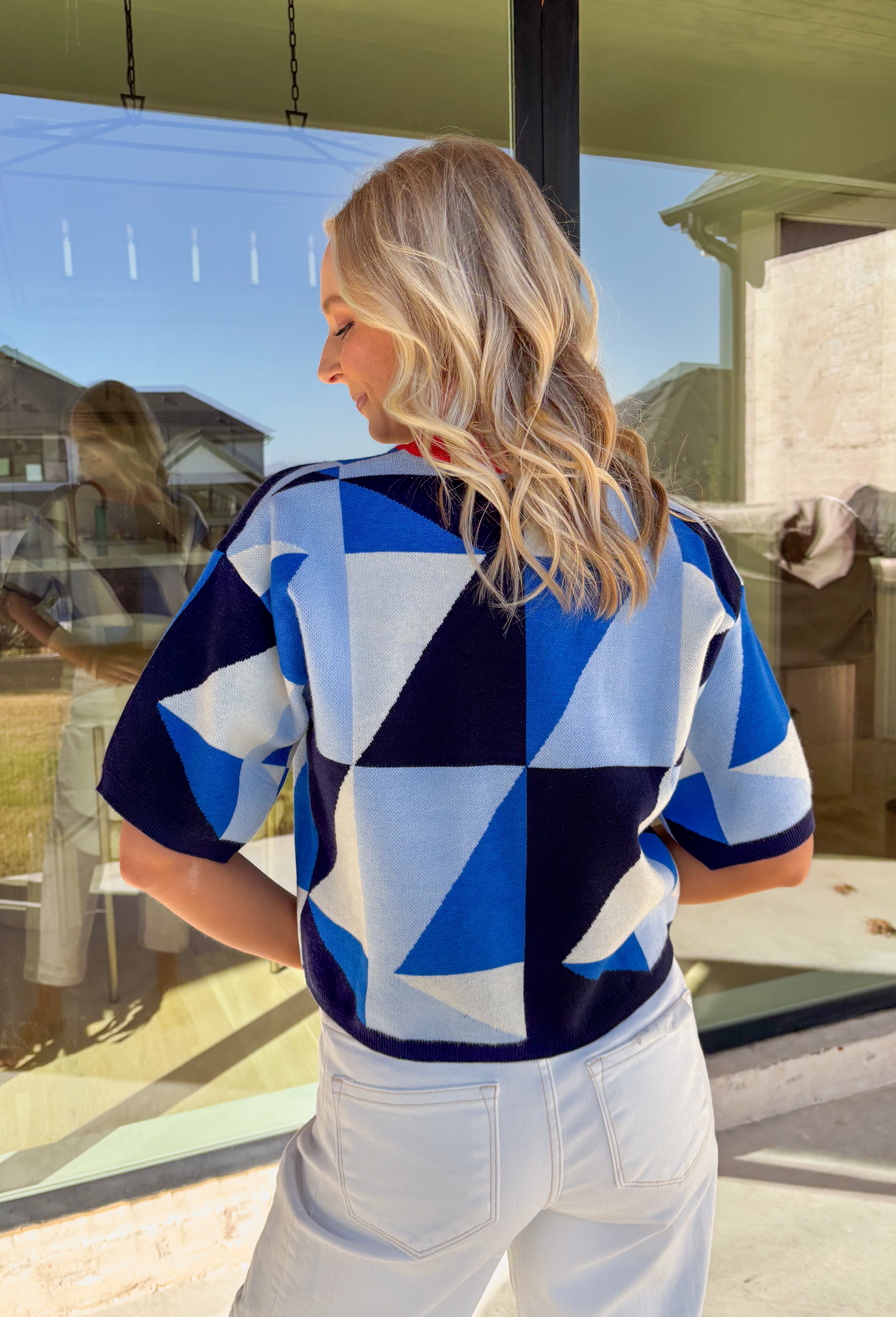 Fun, lightweight, and effortlessly cool, this short sleeve sweater by Entro is the perfect spring knit when you want something a little different. Featuring a blue and navy abstract print throughout, it adds a bold pop of pattern while still feeling easy to style. The red trim along the neckline gives it a sporty little twist, making it a standout piece that pairs perfectly with denim, trousers, or even a skirt for a playful spring look.