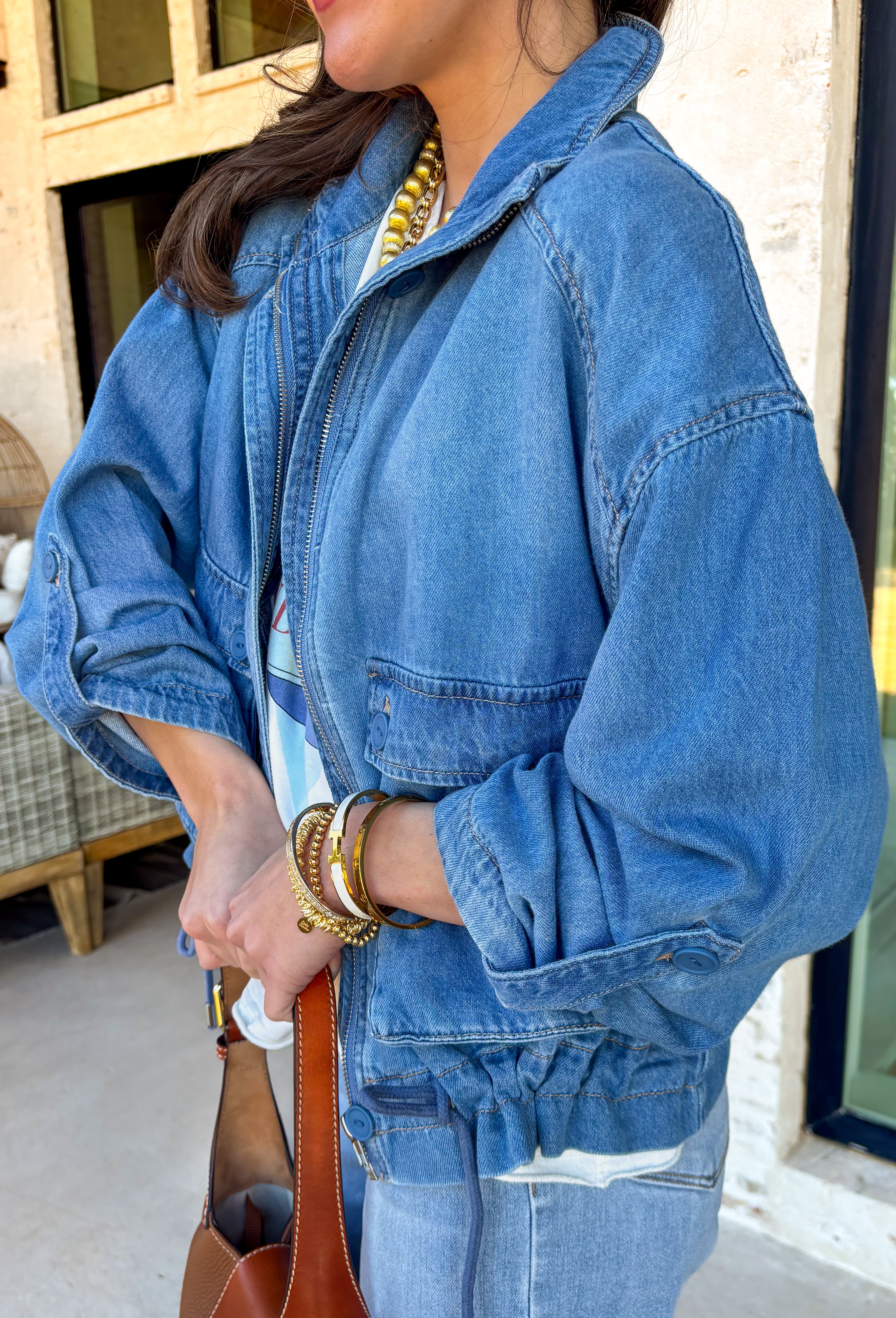 This medium wash denim jacket is the perfect spring layering piece you’ll reach for again and again. Designed with a modern front zipper closure, it offers an easy, throw-on-and-go feel while still looking polished. The mix of front buttoned chest pockets and side pockets adds both function and style, and the adjustable tie detail at the hem lets you customize the fit—cinch it in for shape or leave it relaxed for a laid-back vibe. Made from 100% cotton, this jacket feels structured yet breathable.