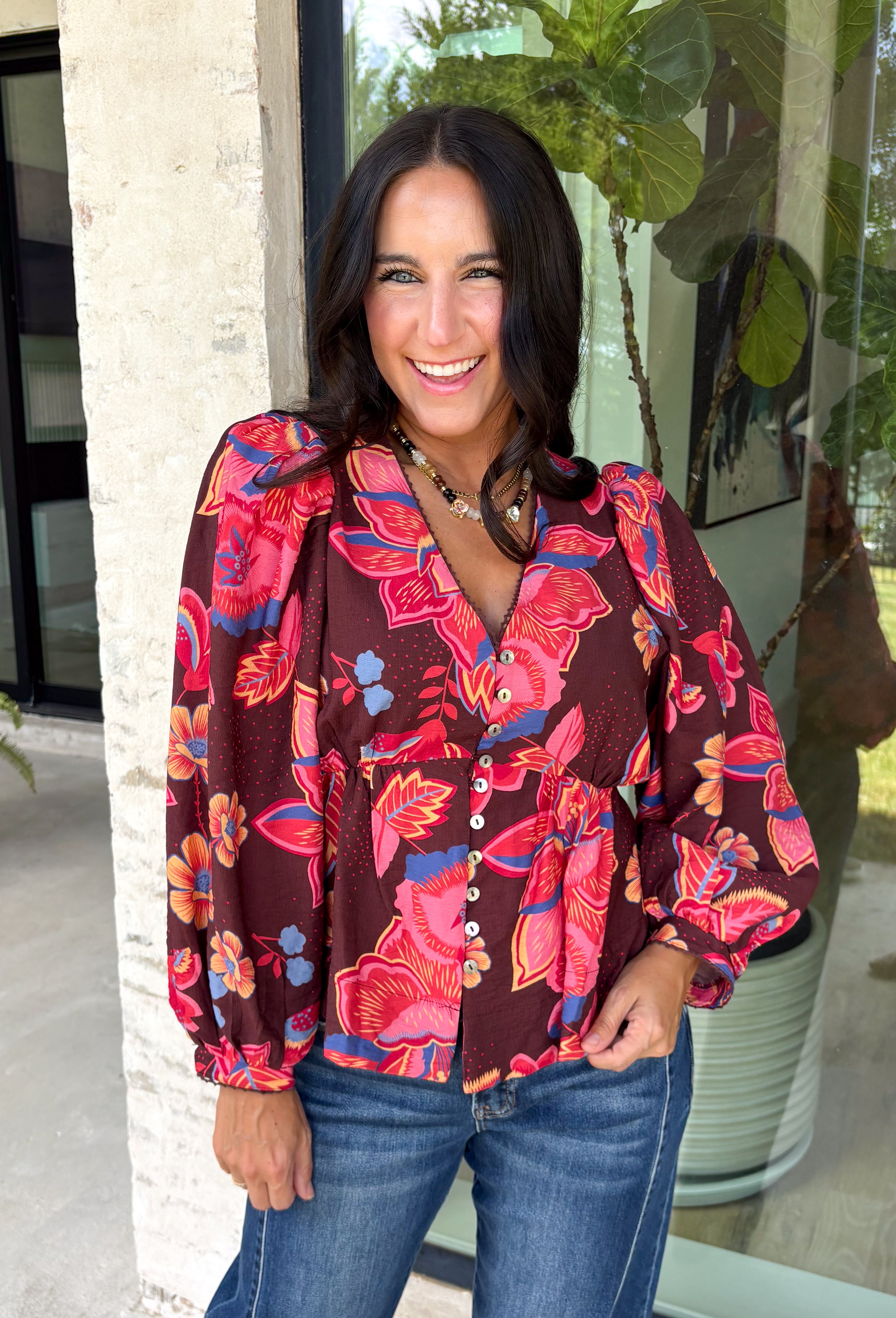 Rich autumn color and pretty details come together in this floral blouse from Entro. The warm brown background is covered in a fall-inspired floral print, making it an easy way to bring the colors of the season into your everyday wardrobe. A v-neckline and button-front closure keep the silhouette classic, while scalloped trim along the neckline and sleeve cuffs adds a sweet finishing touch. 