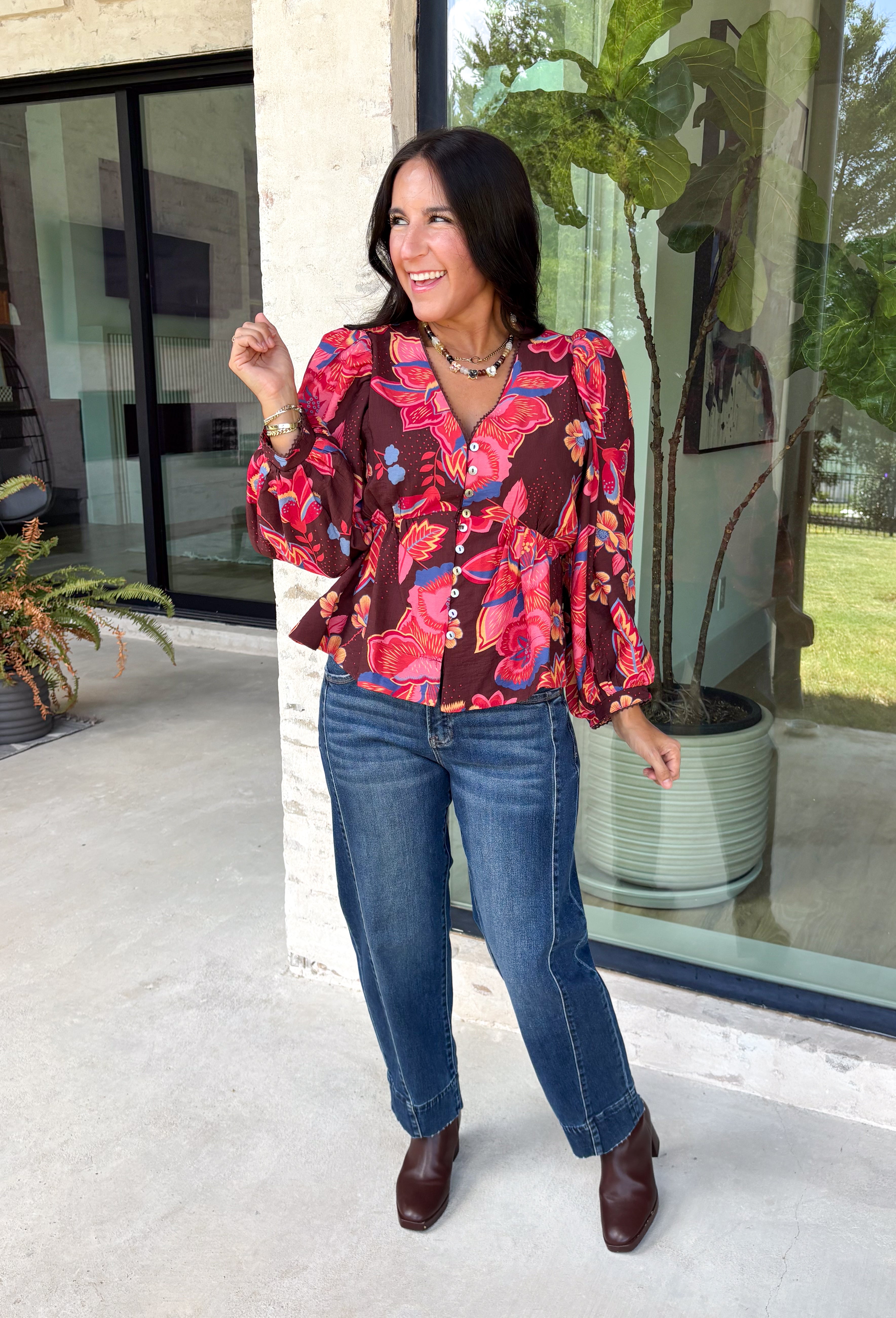 Rich autumn color and pretty details come together in this floral blouse from Entro. The warm brown background is covered in a fall-inspired floral print, making it an easy way to bring the colors of the season into your everyday wardrobe. A v-neckline and button-front closure keep the silhouette classic, while scalloped trim along the neckline and sleeve cuffs adds a sweet finishing touch. 