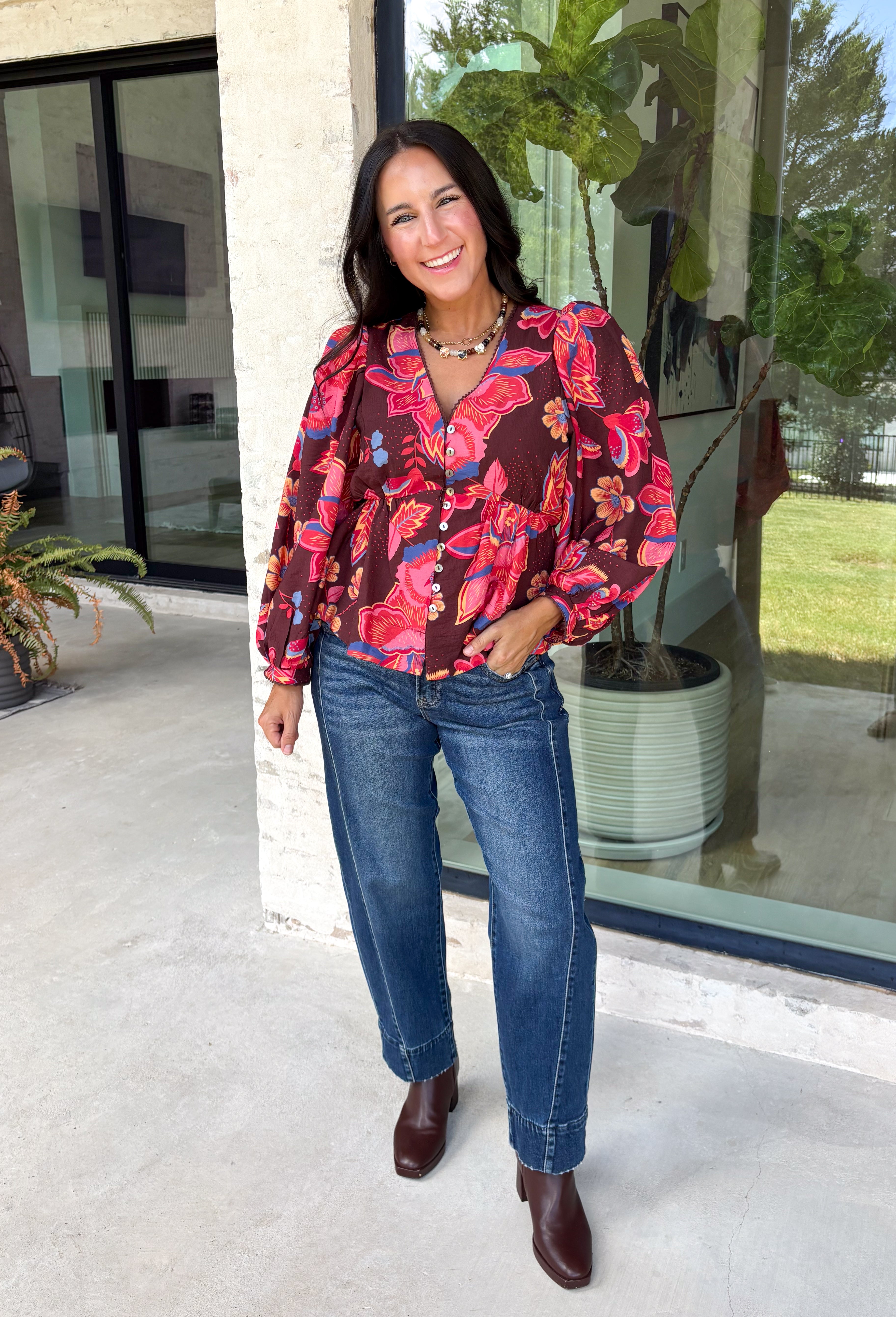 Rich autumn color and pretty details come together in this floral blouse from Entro. The warm brown background is covered in a fall-inspired floral print, making it an easy way to bring the colors of the season into your everyday wardrobe. A v-neckline and button-front closure keep the silhouette classic, while scalloped trim along the neckline and sleeve cuffs adds a sweet finishing touch. 