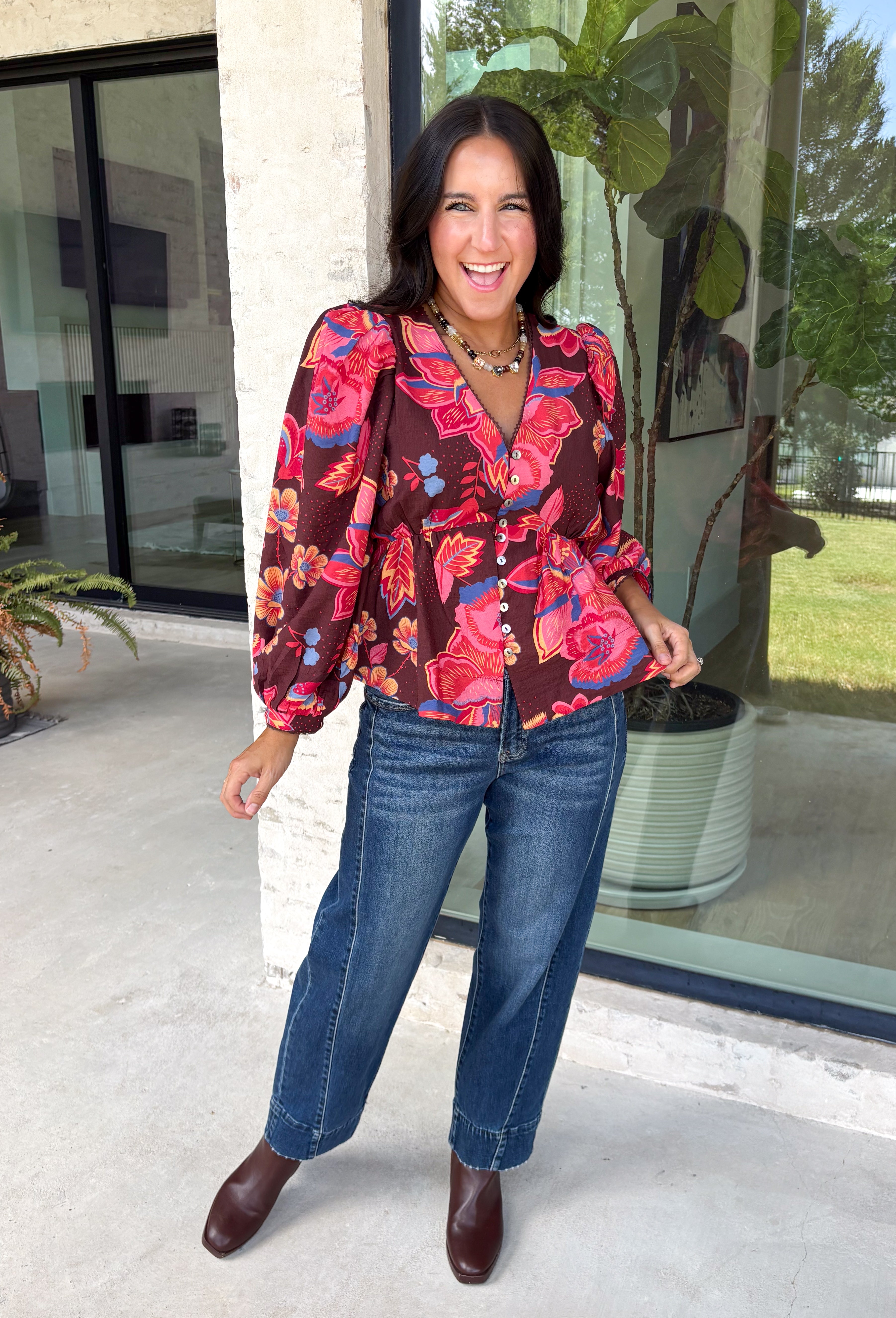 Rich autumn color and pretty details come together in this floral blouse from Entro. The warm brown background is covered in a fall-inspired floral print, making it an easy way to bring the colors of the season into your everyday wardrobe. A v-neckline and button-front closure keep the silhouette classic, while scalloped trim along the neckline and sleeve cuffs adds a sweet finishing touch. 