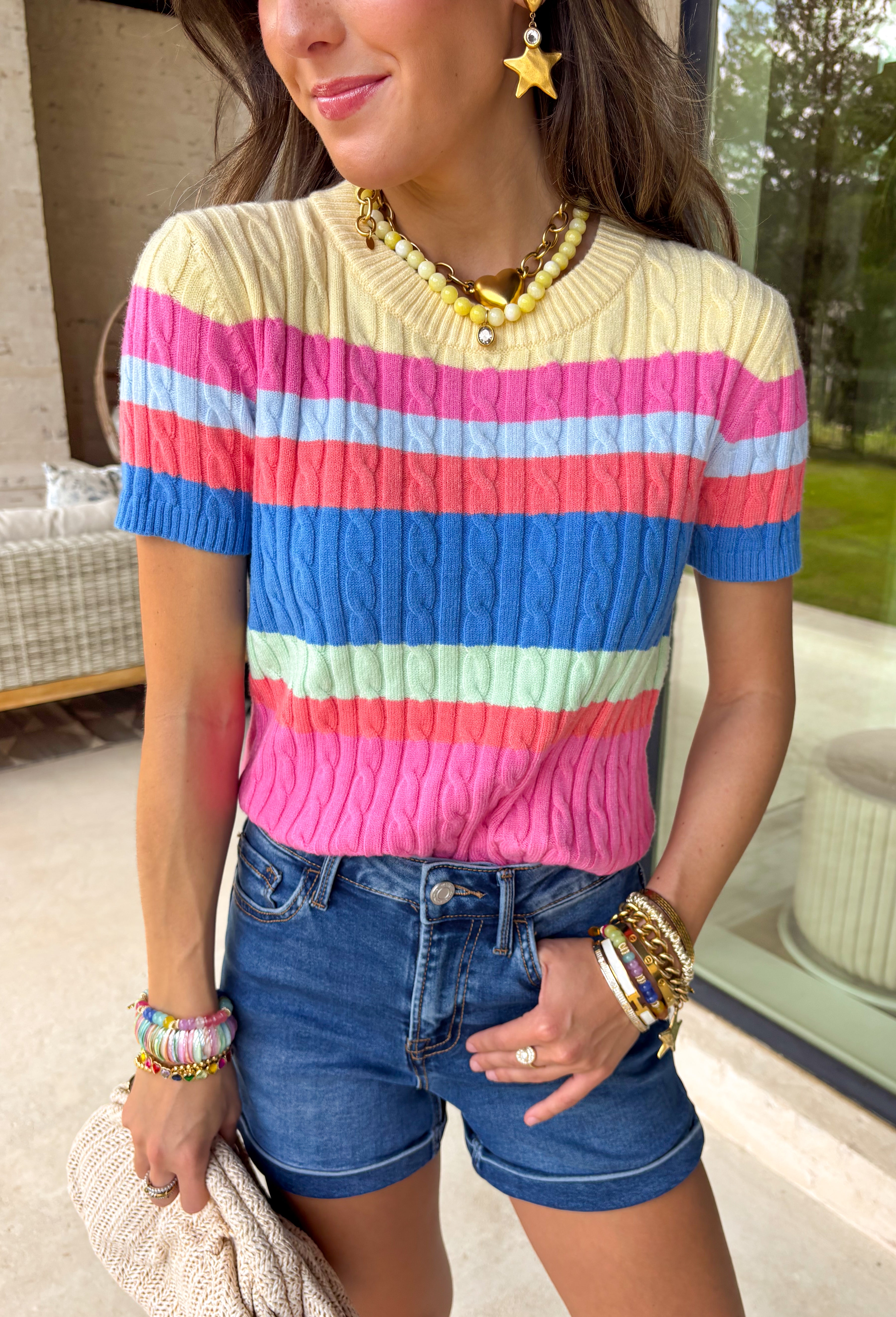 Bright, bold, and guaranteed to boost your mood! This short sleeve cable knit sweater features a fun color block design in cheerful shades of yellow, pink, blue, coral, and green. It’s playful, eye-catching, and perfect for adding a pop of color to your everyday look. The cable knit texture adds a classic touch, while the lightweight feel keeps it easy to wear through the season. It’s the kind of piece that makes getting dressed feel fun again.