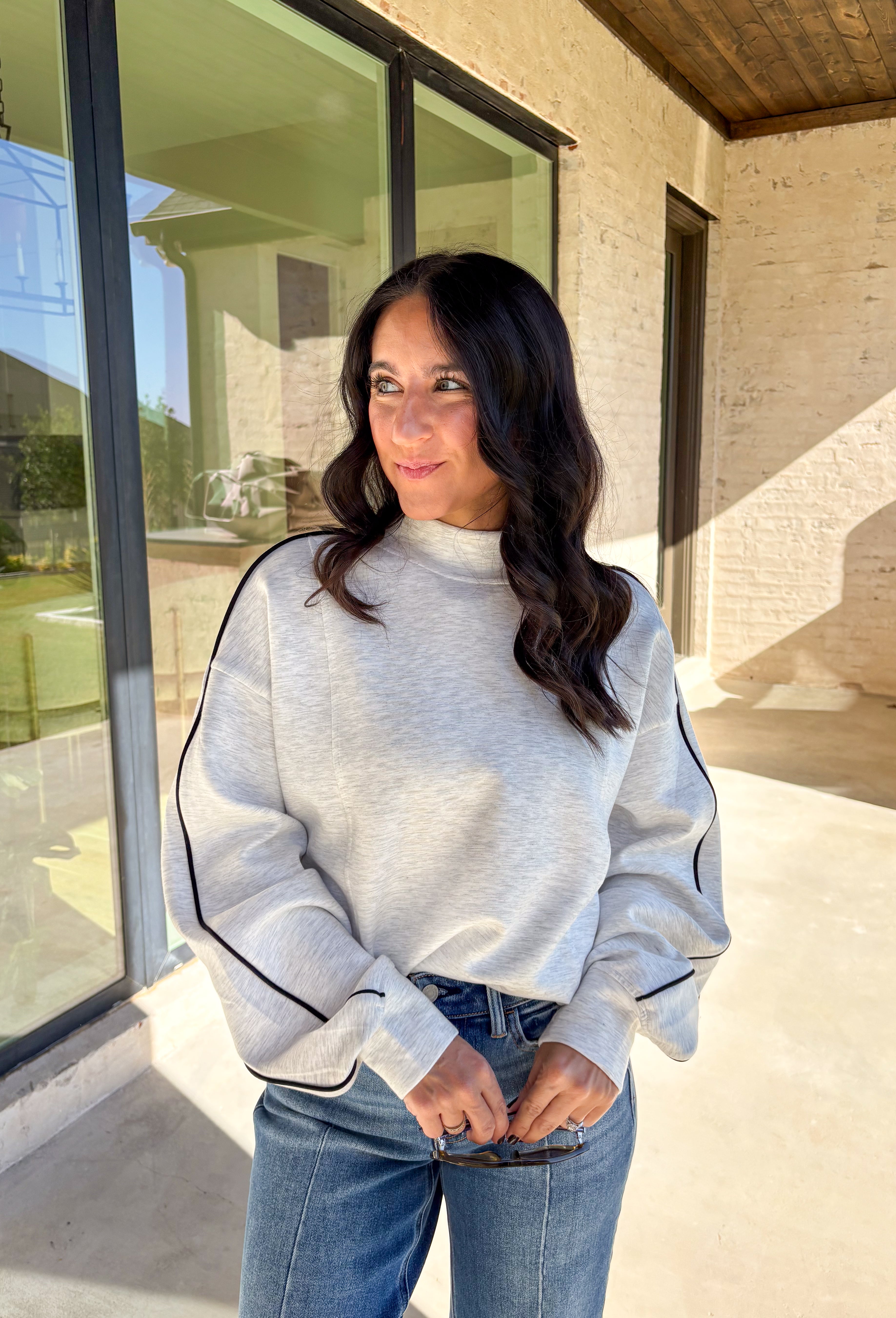 Sporty meets cozy in this heathered light gray pullover. Black stripe details run down the sleeves for a casual, athletic-inspired touch, while the soft modal-blend fabric keeps it comfortable and easy to wear all day long. With its relaxed fit and cozy feel, this piece is perfect for layering or wearing solo on cool fall days.