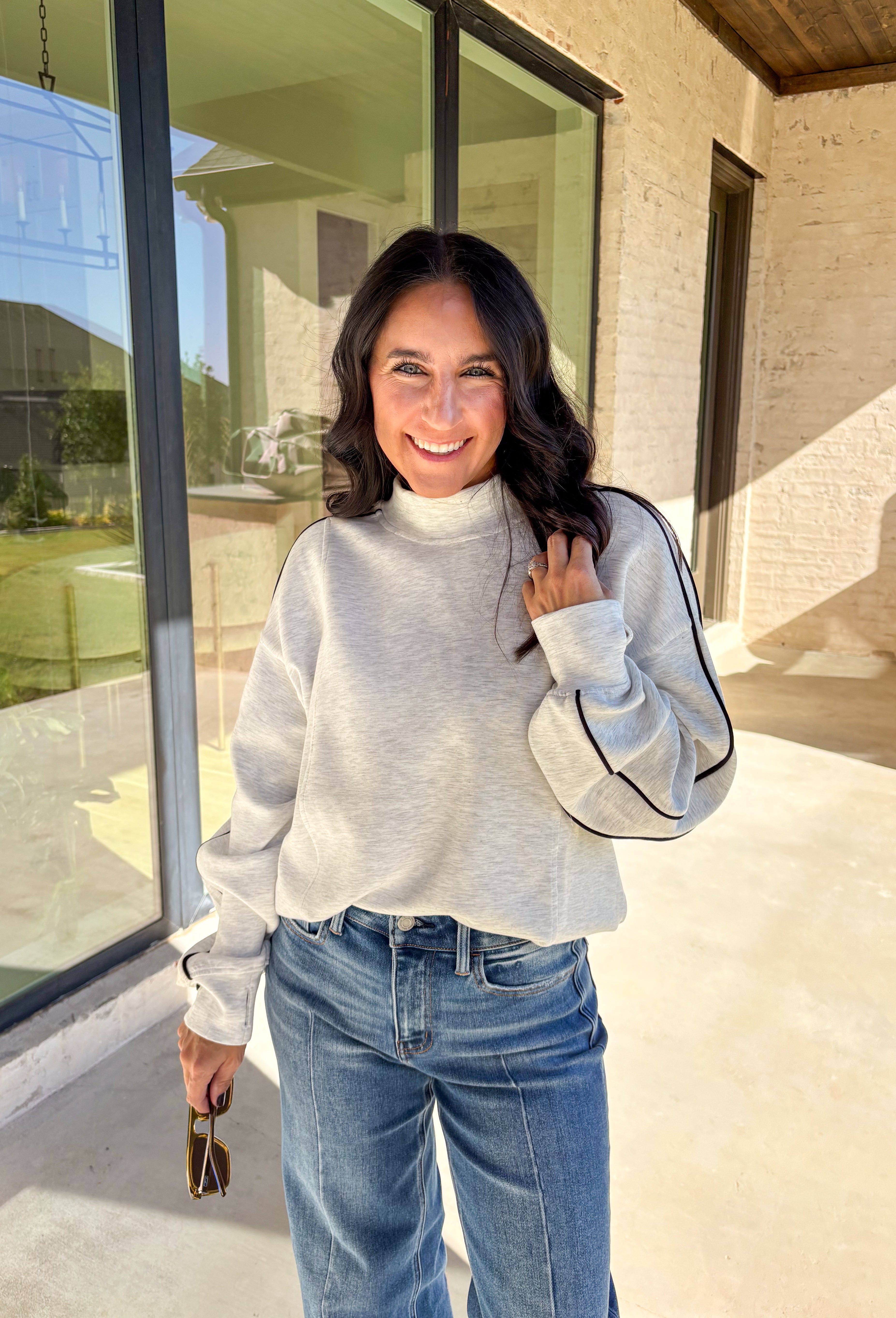 Sporty meets cozy in this heathered light gray pullover. Black stripe details run down the sleeves for a casual, athletic-inspired touch, while the soft modal-blend fabric keeps it comfortable and easy to wear all day long. With its relaxed fit and cozy feel, this piece is perfect for layering or wearing solo on cool fall days.