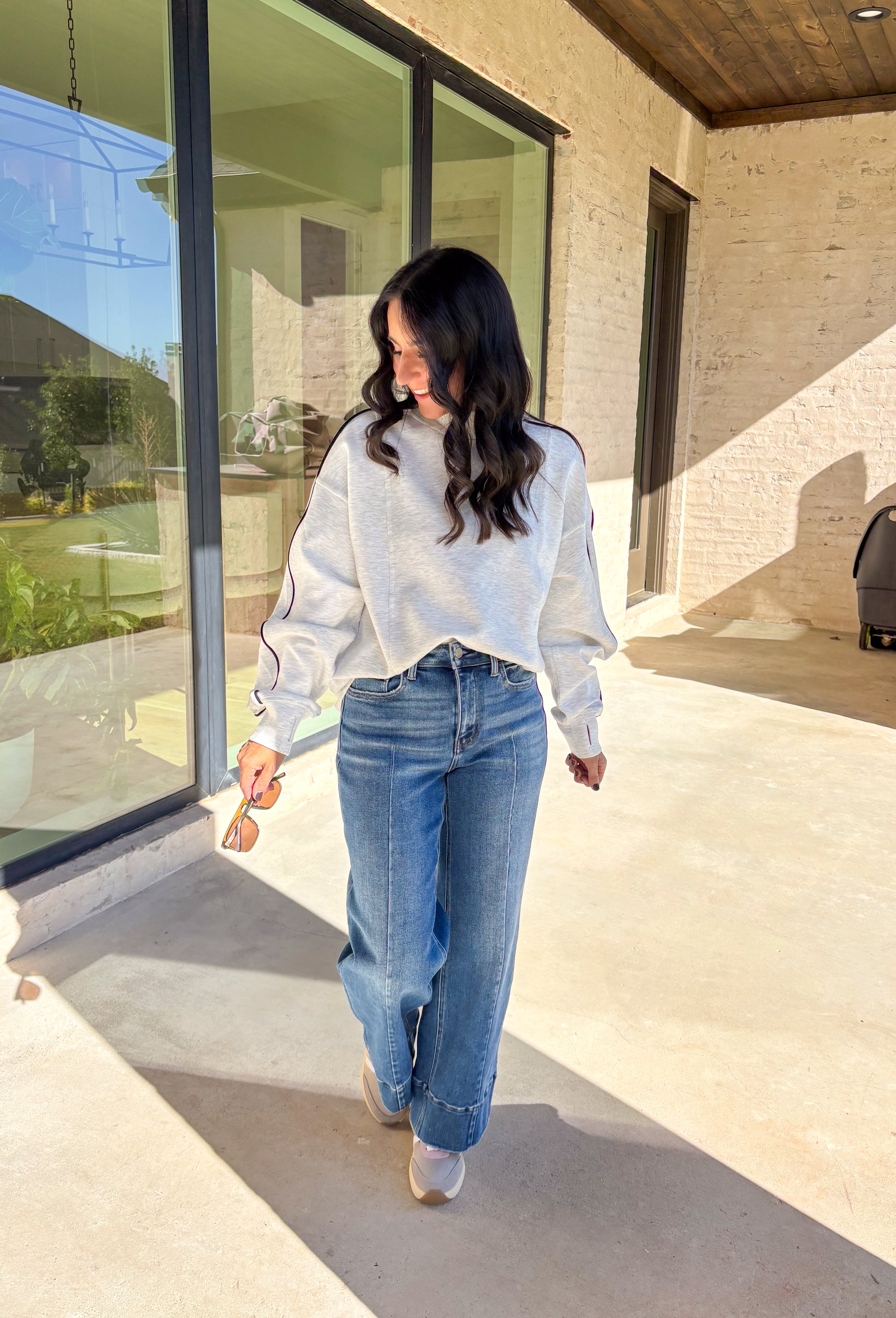 Sporty meets cozy in this heathered light gray pullover. Black stripe details run down the sleeves for a casual, athletic-inspired touch, while the soft modal-blend fabric keeps it comfortable and easy to wear all day long. With its relaxed fit and cozy feel, this piece is perfect for layering or wearing solo on cool fall days.
