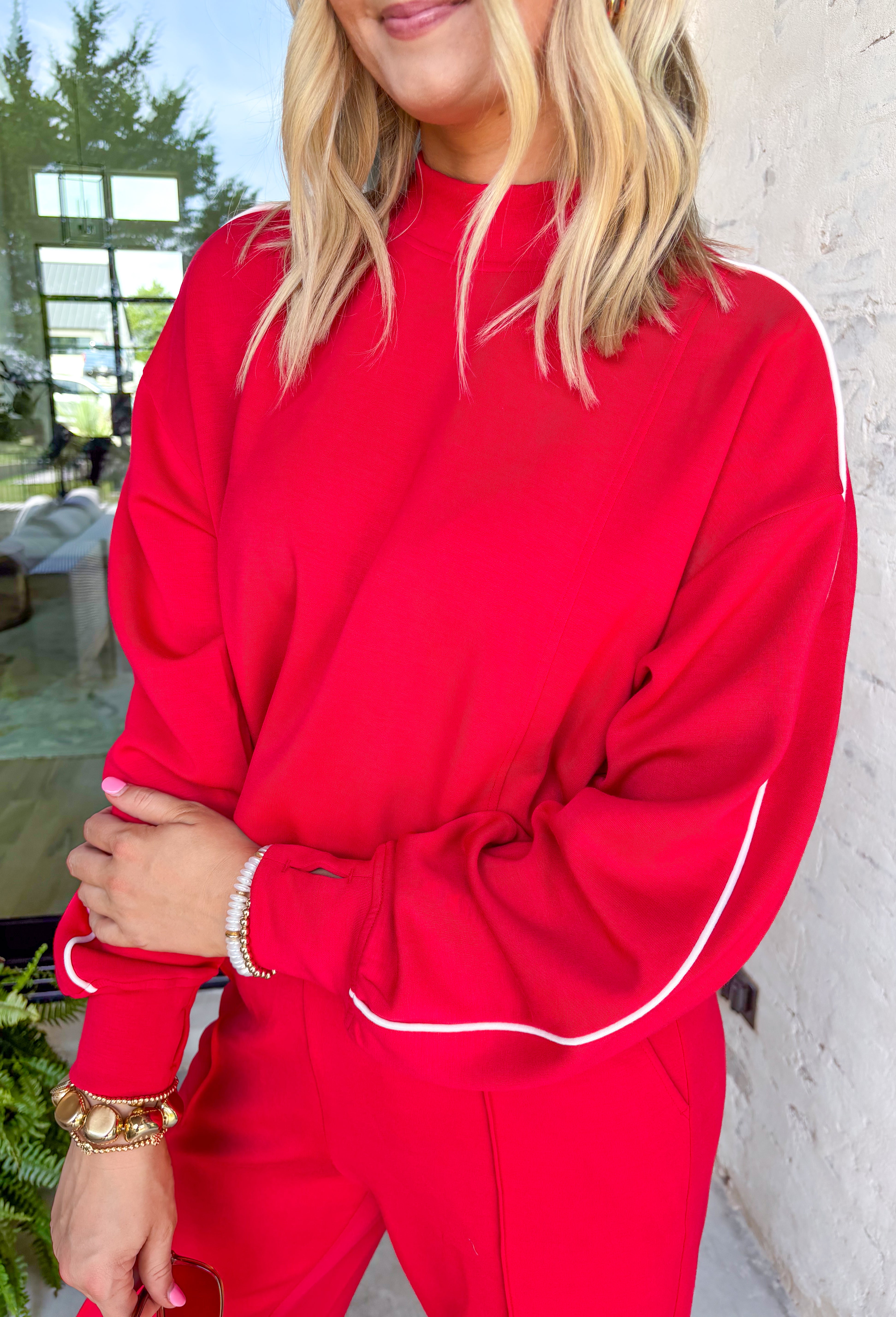 Sporty meets cozy in this red pullover. White stripe details run down the sleeves for a casual, athletic-inspired touch, while the soft modal-blend fabric keeps it comfortable and easy to wear all day long. With its relaxed fit and cozy feel, this piece is perfect for layering or wearing solo on cool fall days.&nbsp;