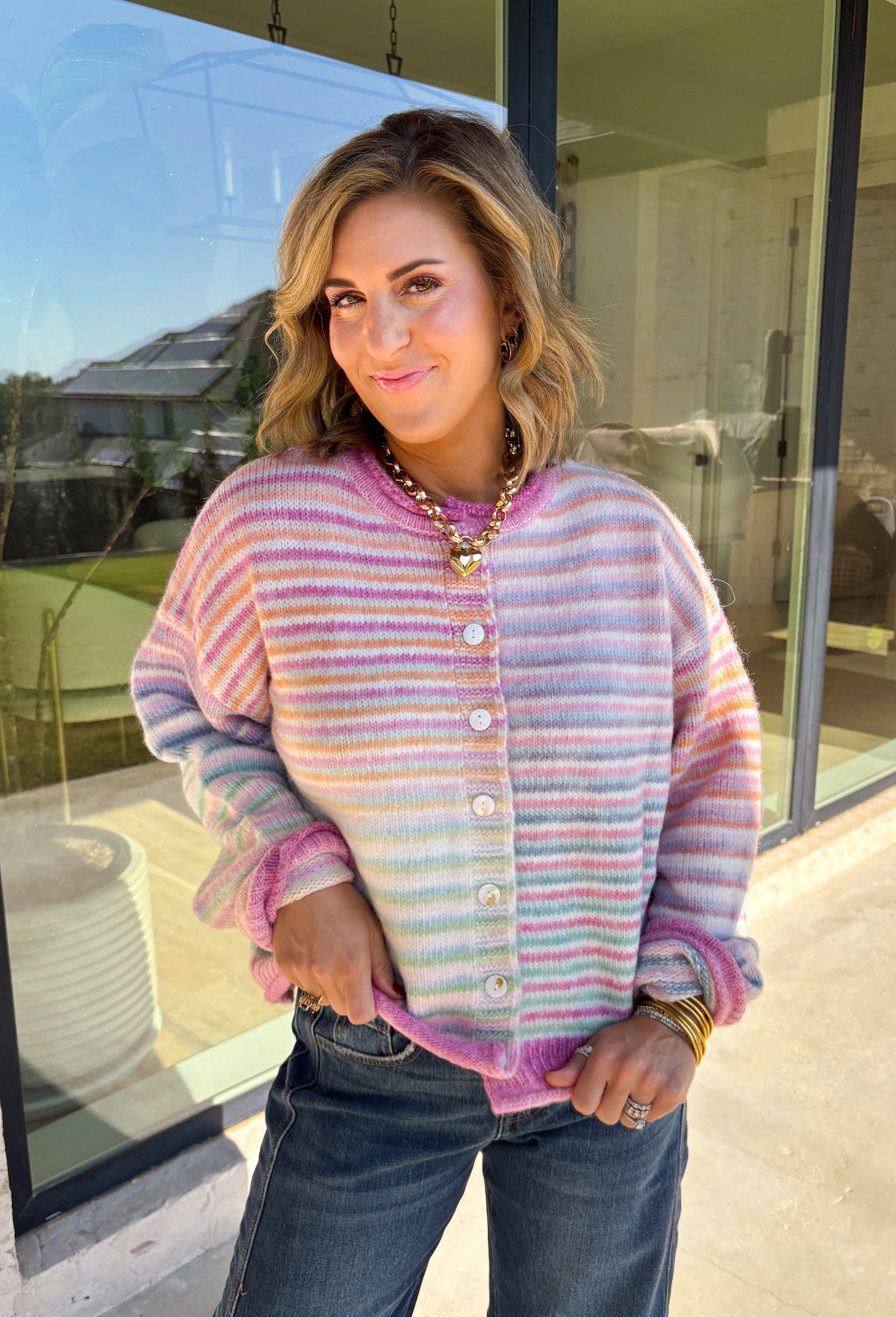 Bring a little extra color to cozy season with this striped knit cardigan from Twenitfourth. A playful mix of pink, purple, coral, blue, lavender, and off white gives this sweater a cheerful look that instantly brightens up cooler days. The button-down front makes it easy to wear closed as a top or open over your favorite tee or tank for a layered look.