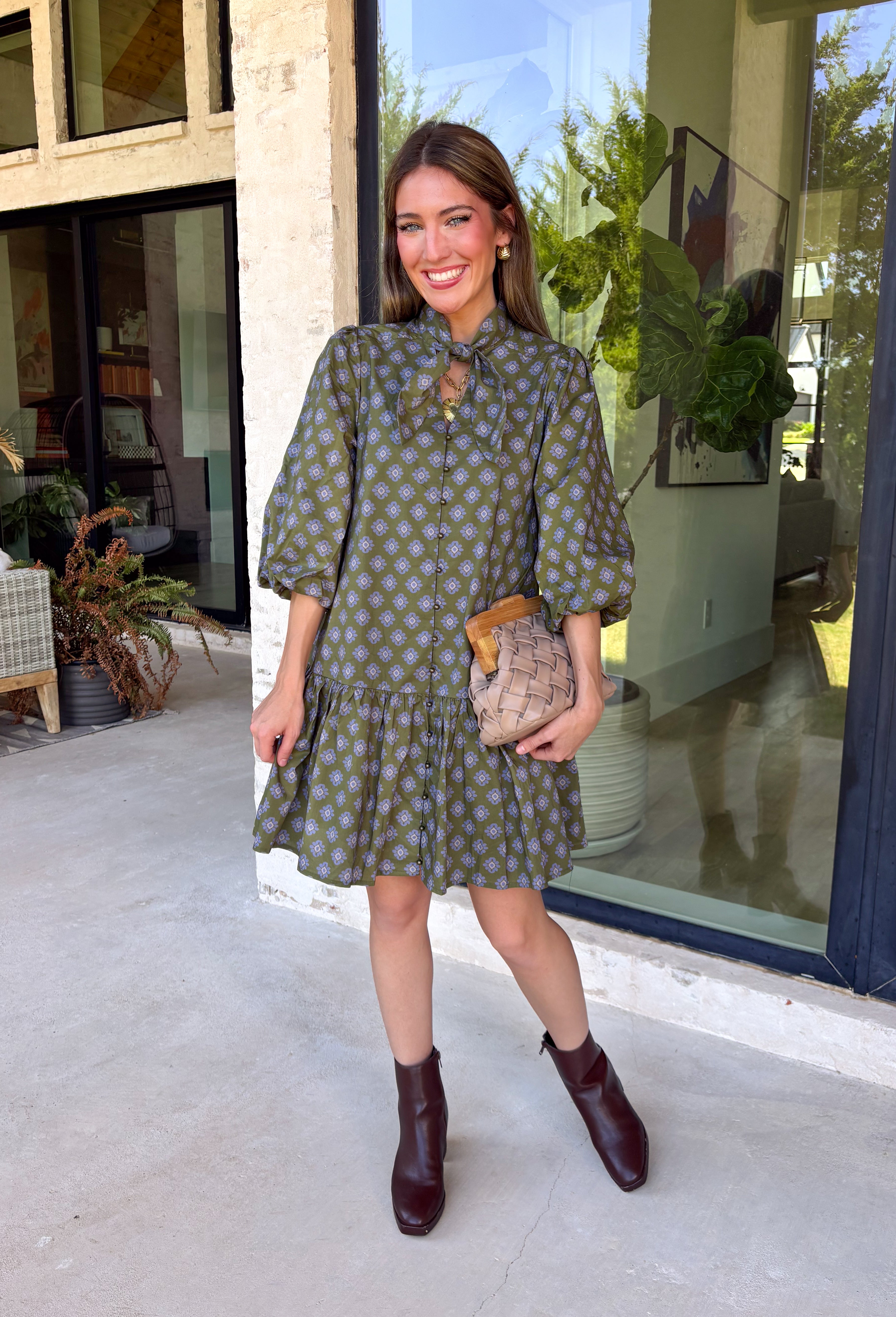 Unexpected color makes this floral dress from Entro such a fun pick for the season. The olive green background is covered in an abstract periwinkle floral print, creating a pretty mix of earthy and cool tones that stands out from traditional fall florals. A shirt collar and self-tie neckline add extra detail, while the button-front closure and ¾ puff sleeves give the silhouette a classic feel. The ruffle hem adds a playful finish, and the lined design provides comfortable coverage.