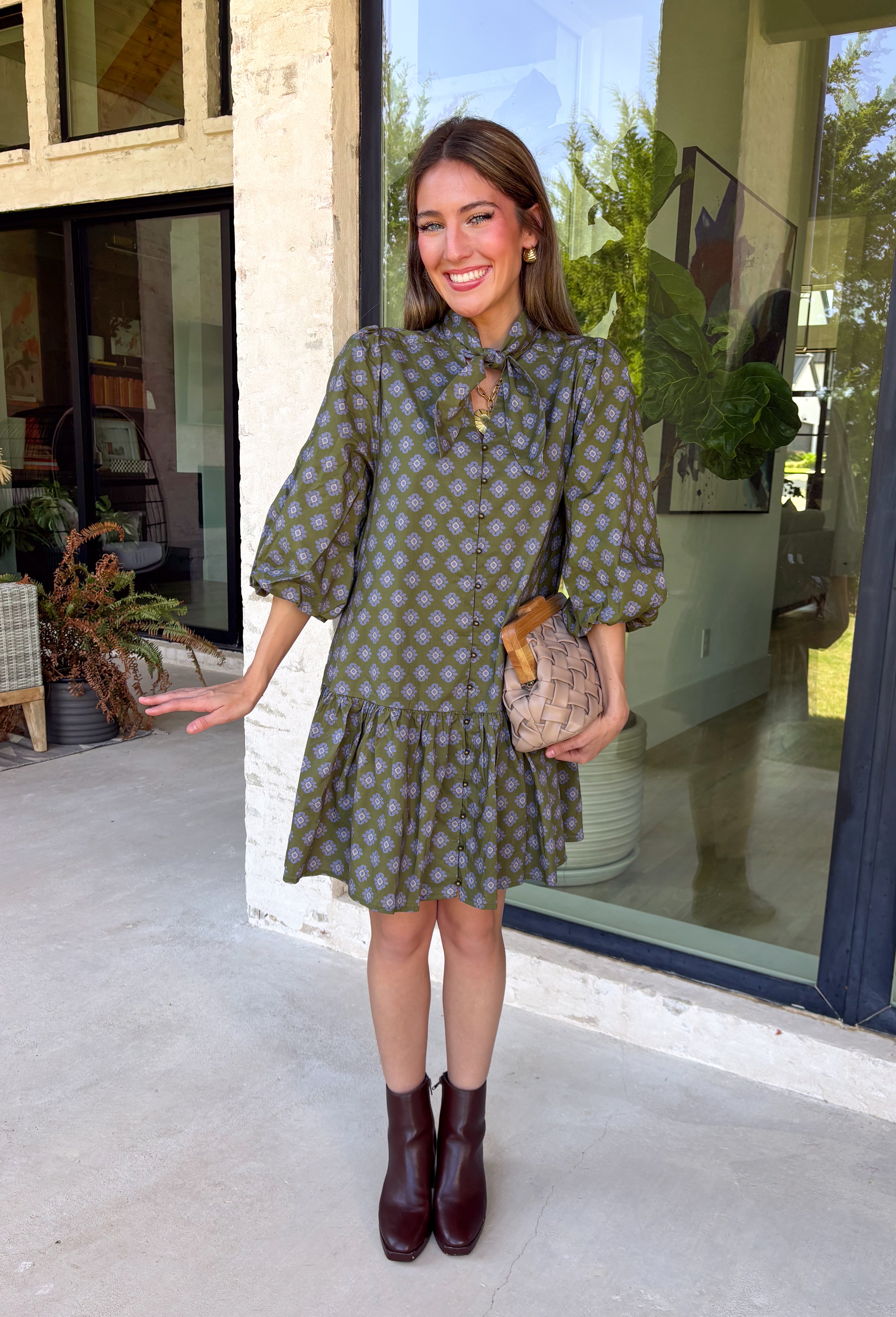 Unexpected color makes this floral dress from Entro such a fun pick for the season. The olive green background is covered in an abstract periwinkle floral print, creating a pretty mix of earthy and cool tones that stands out from traditional fall florals. A shirt collar and self-tie neckline add extra detail, while the button-front closure and ¾ puff sleeves give the silhouette a classic feel. The ruffle hem adds a playful finish, and the lined design provides comfortable coverage.