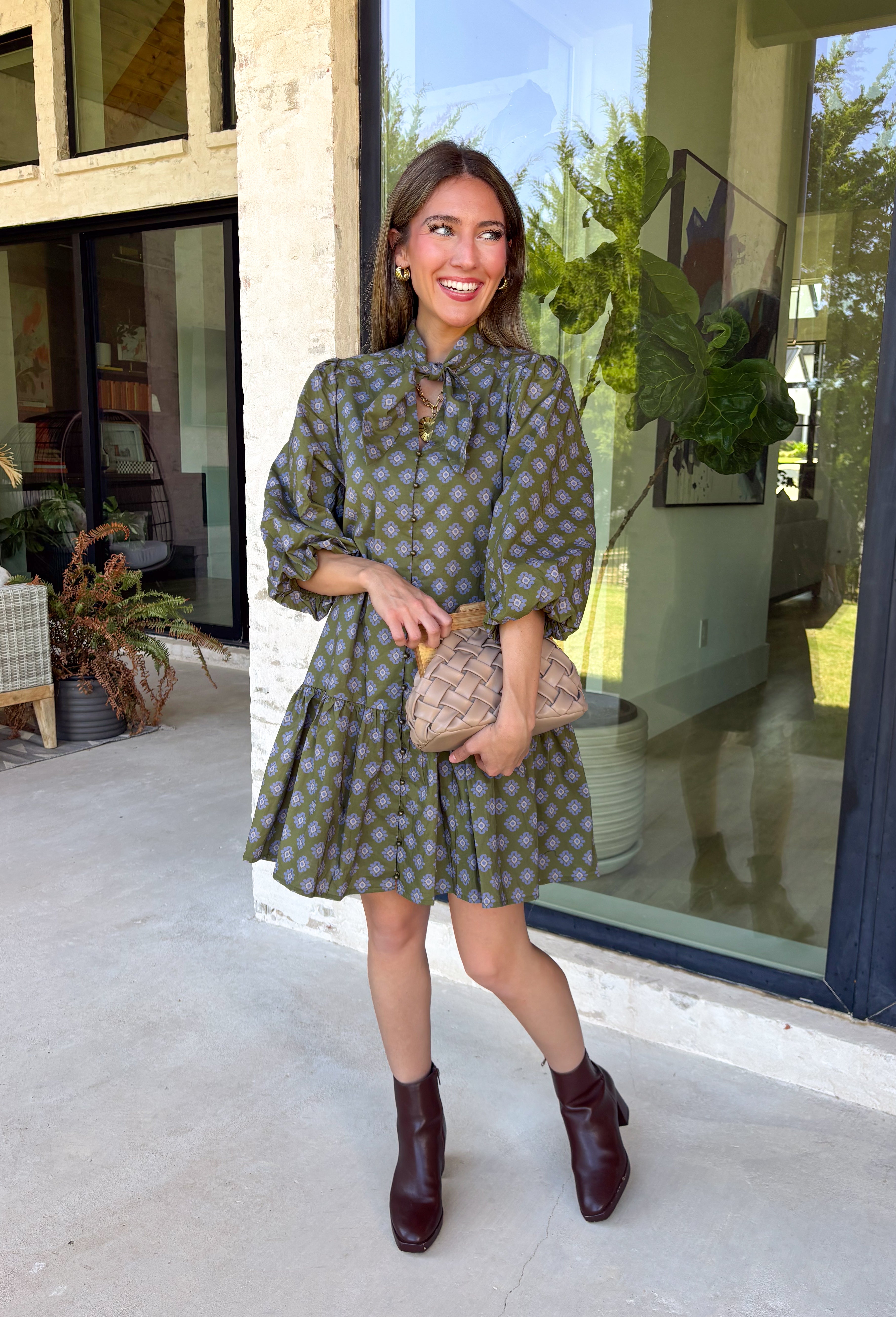 Unexpected color makes this floral dress from Entro such a fun pick for the season. The olive green background is covered in an abstract periwinkle floral print, creating a pretty mix of earthy and cool tones that stands out from traditional fall florals. A shirt collar and self-tie neckline add extra detail, while the button-front closure and ¾ puff sleeves give the silhouette a classic feel. The ruffle hem adds a playful finish, and the lined design provides comfortable coverage.