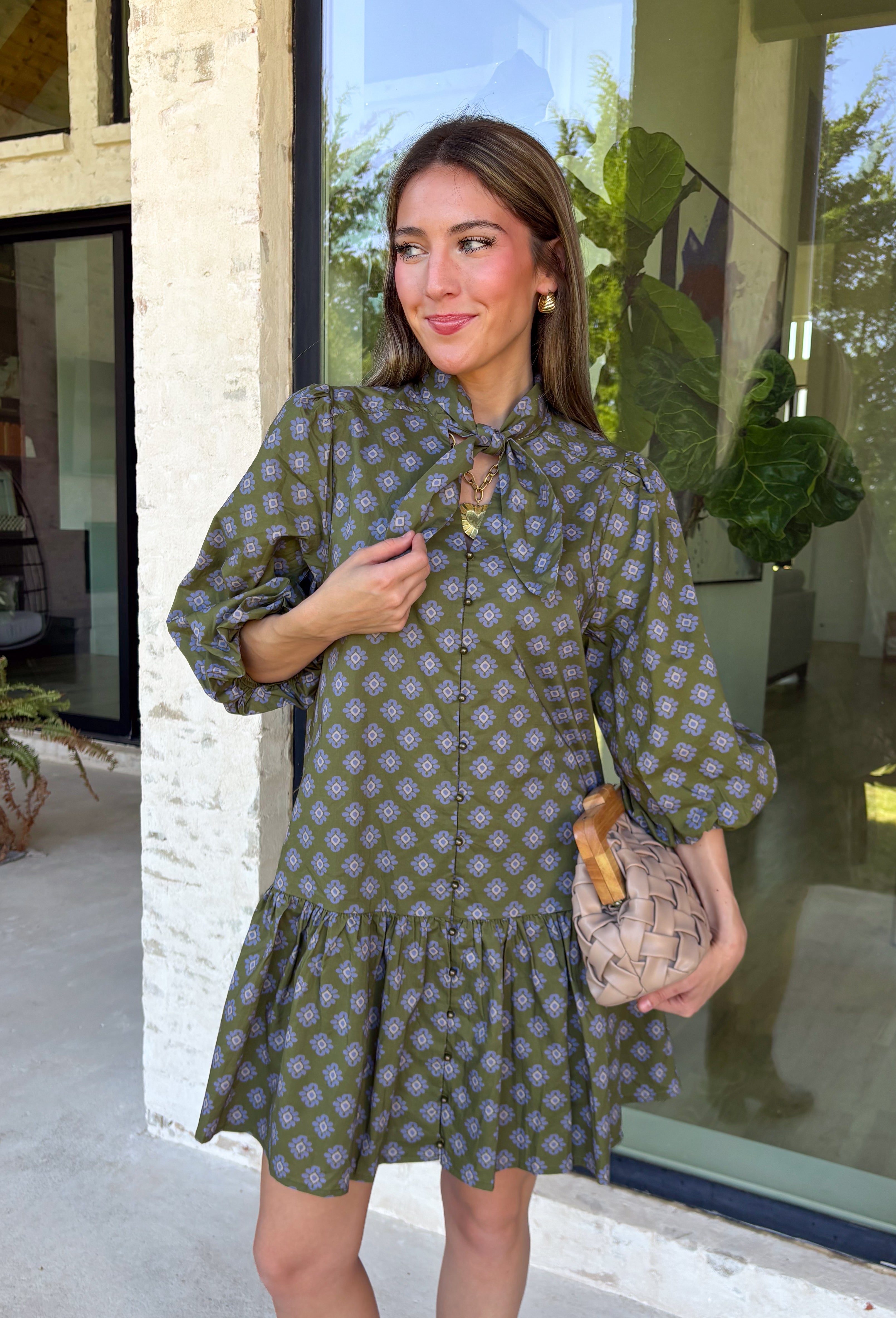 Unexpected color makes this floral dress from Entro such a fun pick for the season. The olive green background is covered in an abstract periwinkle floral print, creating a pretty mix of earthy and cool tones that stands out from traditional fall florals. A shirt collar and self-tie neckline add extra detail, while the button-front closure and ¾ puff sleeves give the silhouette a classic feel. The ruffle hem adds a playful finish, and the lined design provides comfortable coverage.
