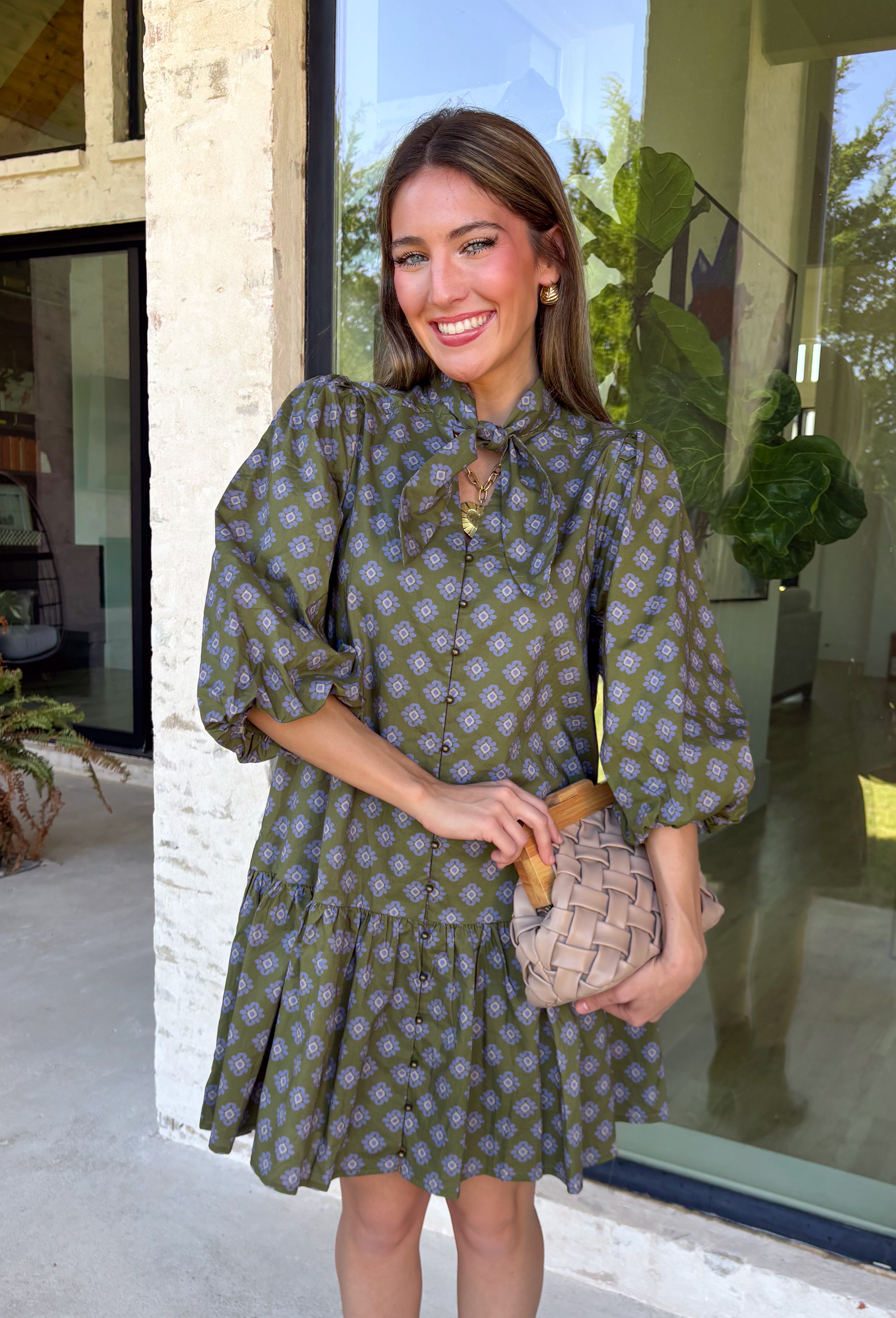 Unexpected color makes this floral dress from Entro such a fun pick for the season. The olive green background is covered in an abstract periwinkle floral print, creating a pretty mix of earthy and cool tones that stands out from traditional fall florals. A shirt collar and self-tie neckline add extra detail, while the button-front closure and ¾ puff sleeves give the silhouette a classic feel. The ruffle hem adds a playful finish, and the lined design provides comfortable coverage.
